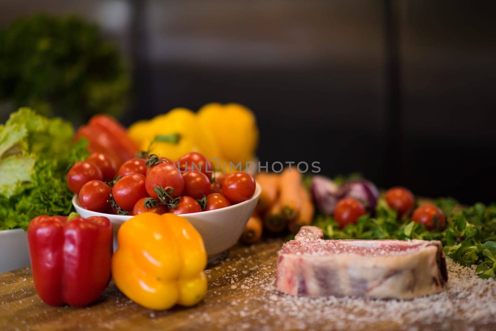 Juicy slice of raw steak  with vegetables around on a wooden table