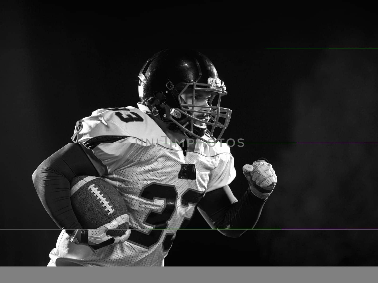 American football player holding ball while running on field at night