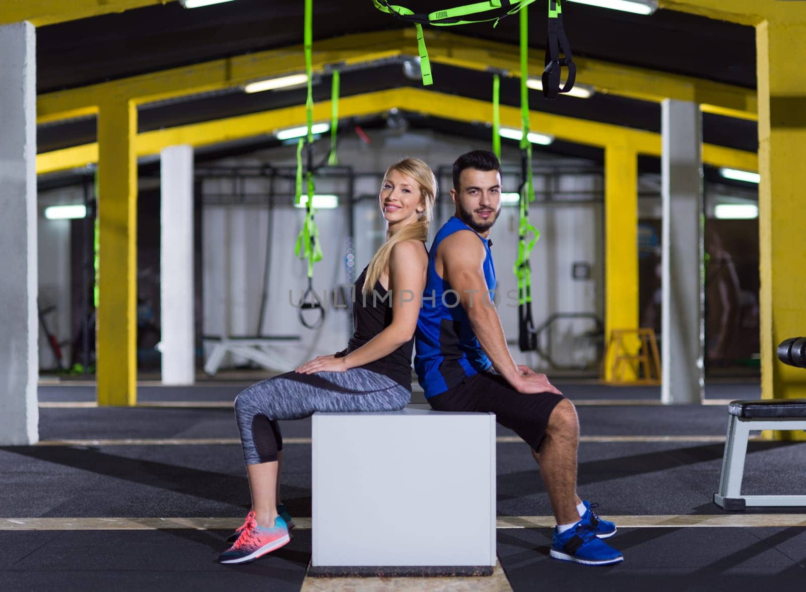 portrait of young healthy athletic people training jumping on fit box at gym