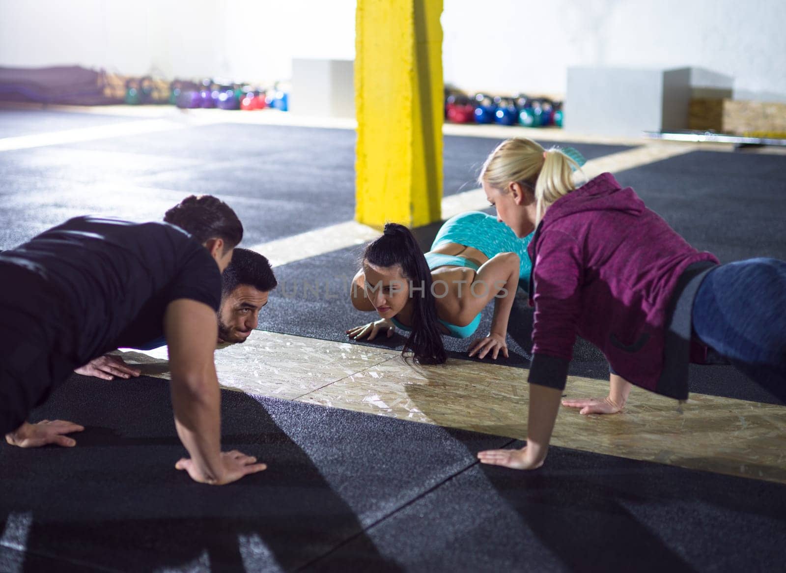 group of young healthy people doing pushups at fitness  gym