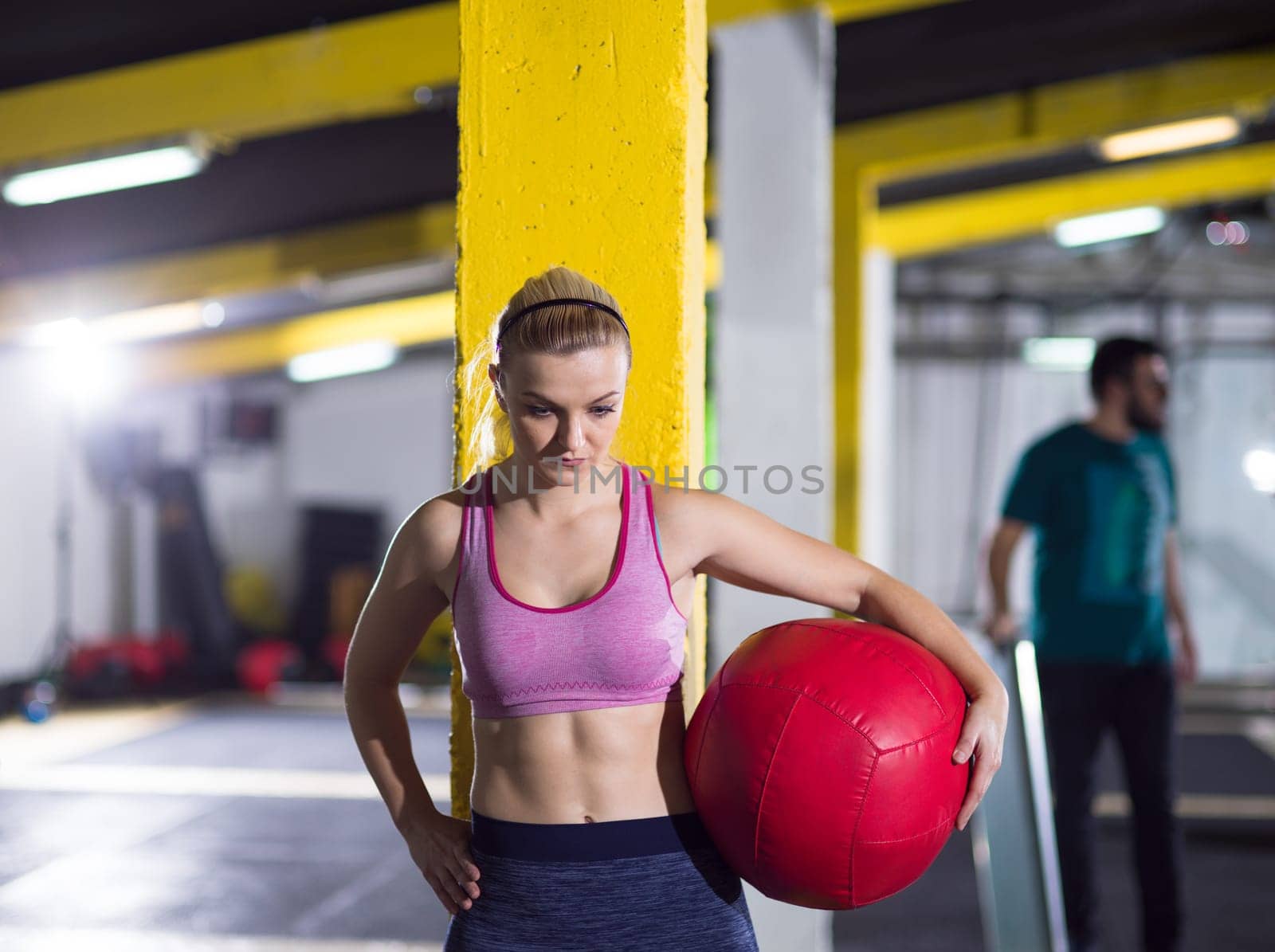 Portrait of beautiful athlete woman with red medicine  ball at crossfitness gym