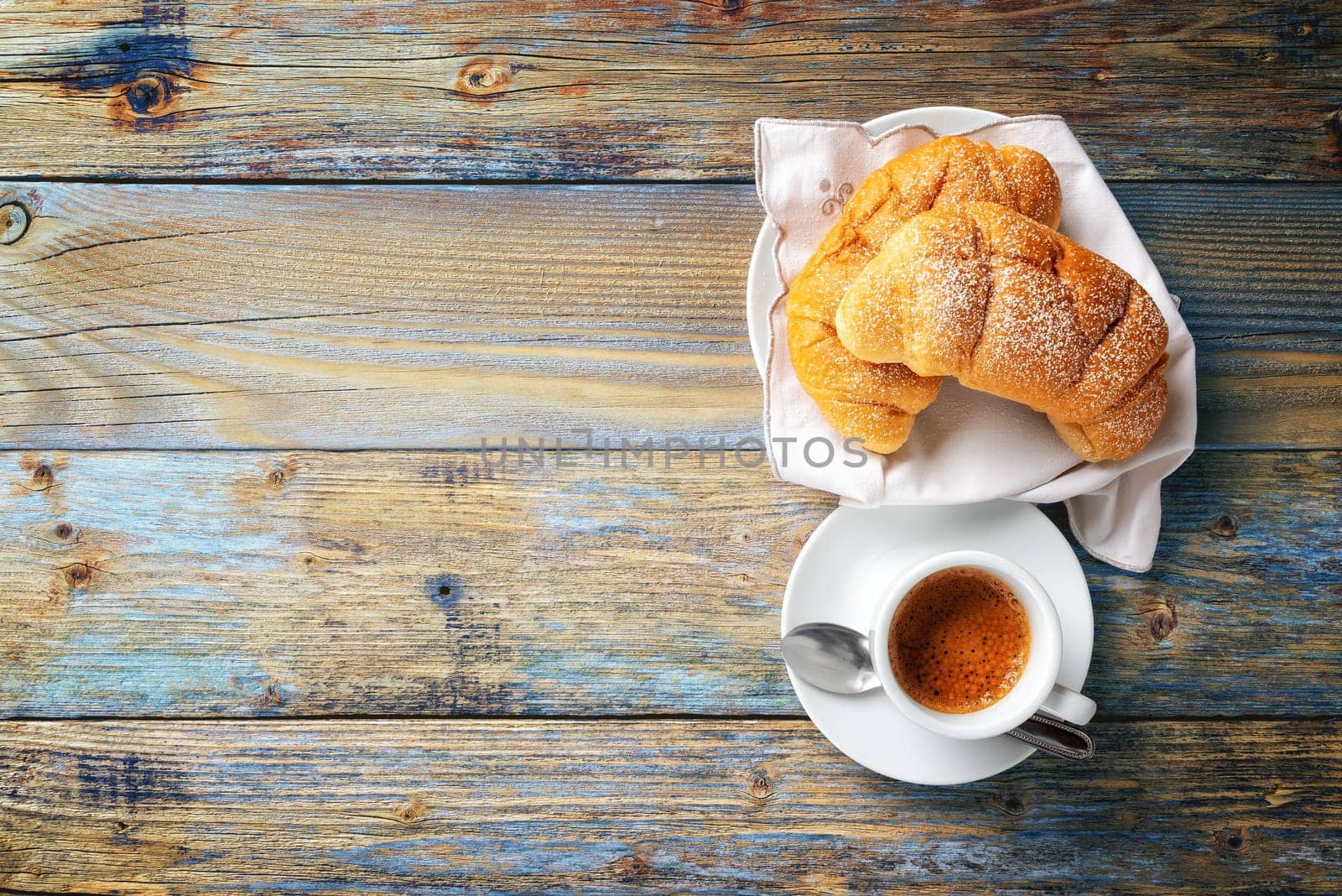 View from above. Cup of hot Italian espresso coffee and croissants on a light blue rustic wooden background. Food and drink. Lifestyle.