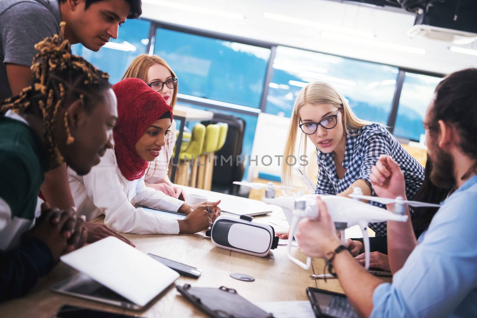 multiethnic startup business team discussing new business plan,working on laptop and tablet computer while learning about drone technology for new business advancement
