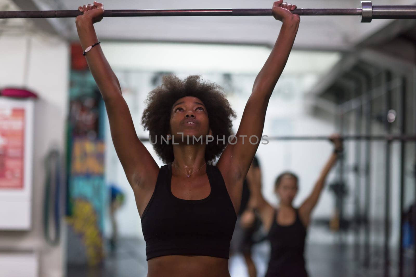 Young Cute african american sport woman in fitness room lifting empty bar