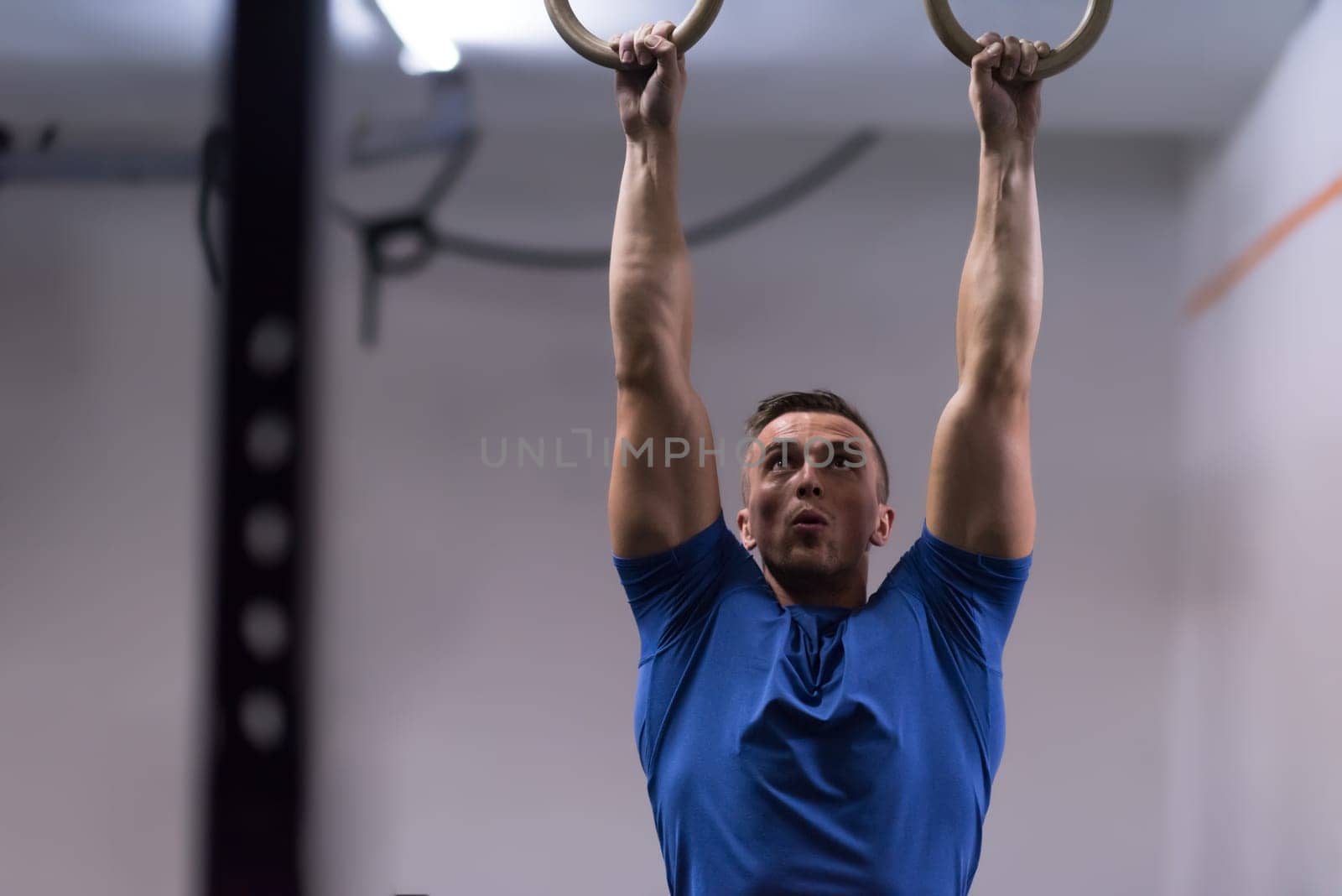 Fitness handsome man doing dipping exercise using rings in the gym