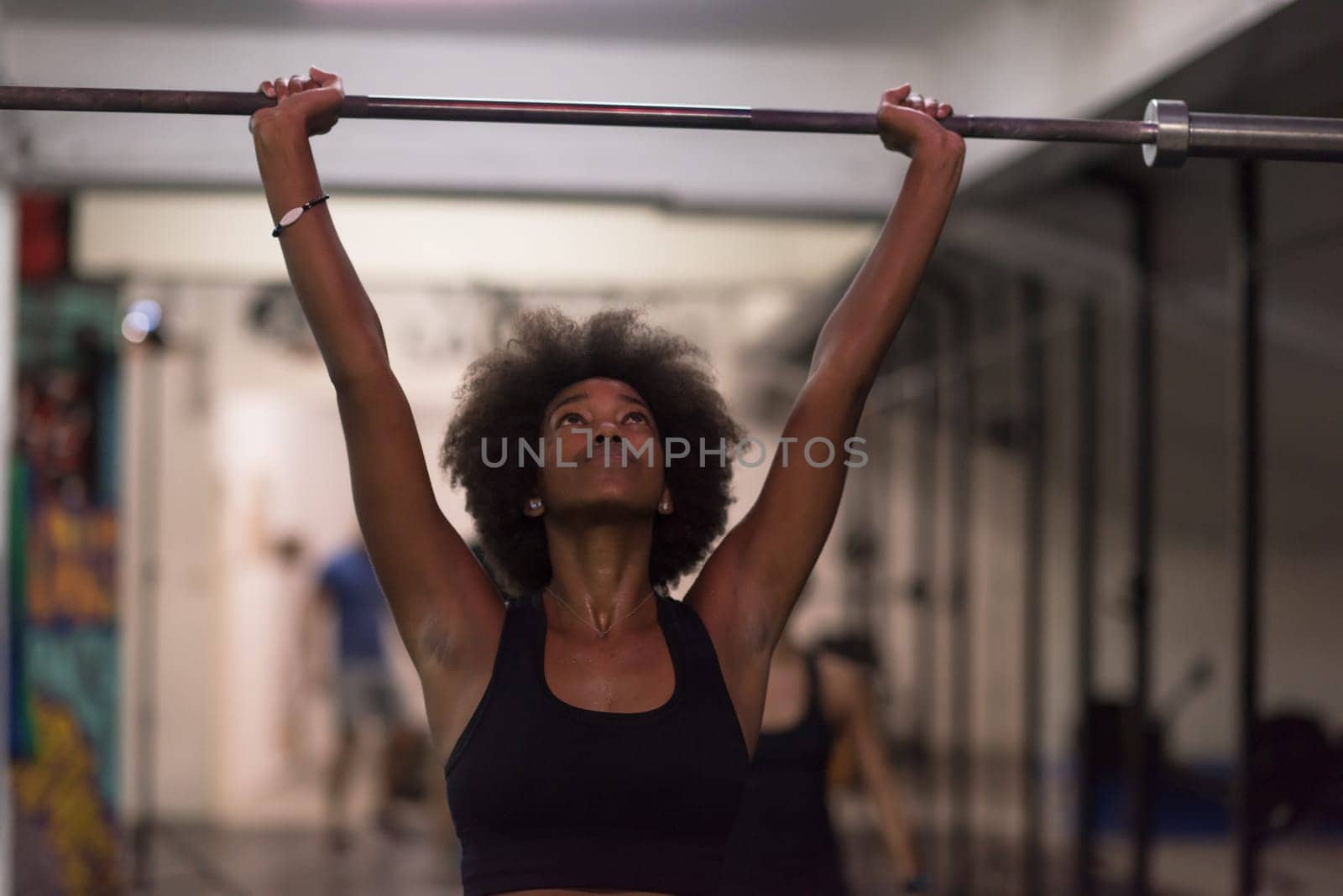 Young Cute african american sport woman in fitness room lifting empty bar