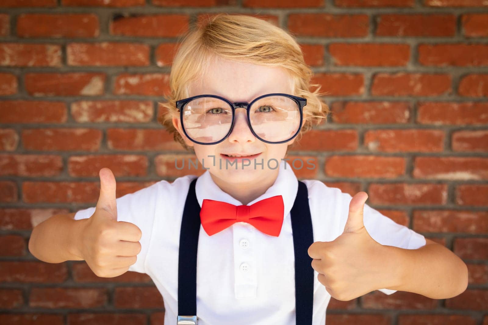 Cute Young Caucasian Boy With Thumbs Up Wearing Glasses and Red, White and Blue.