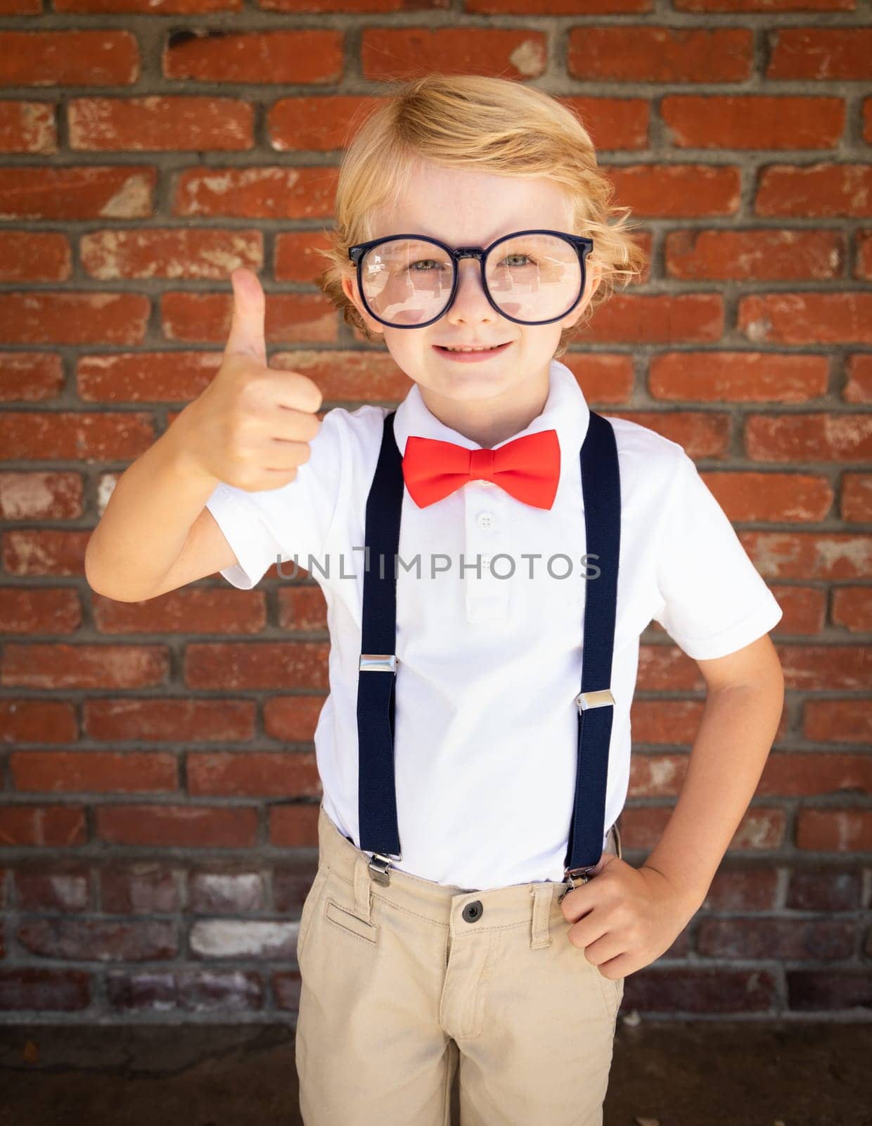 Cute Young Caucasian Boy With Thumbs Up Wearing Glasses and Red, White and Blue.