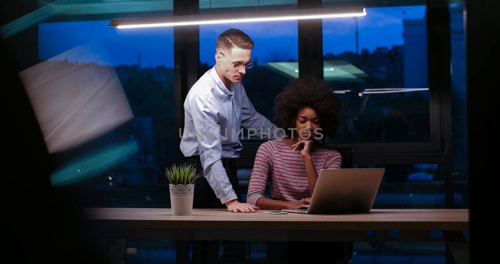Multiethnic startup business team on meeting in modern night office interior brainstorming, working on laptop