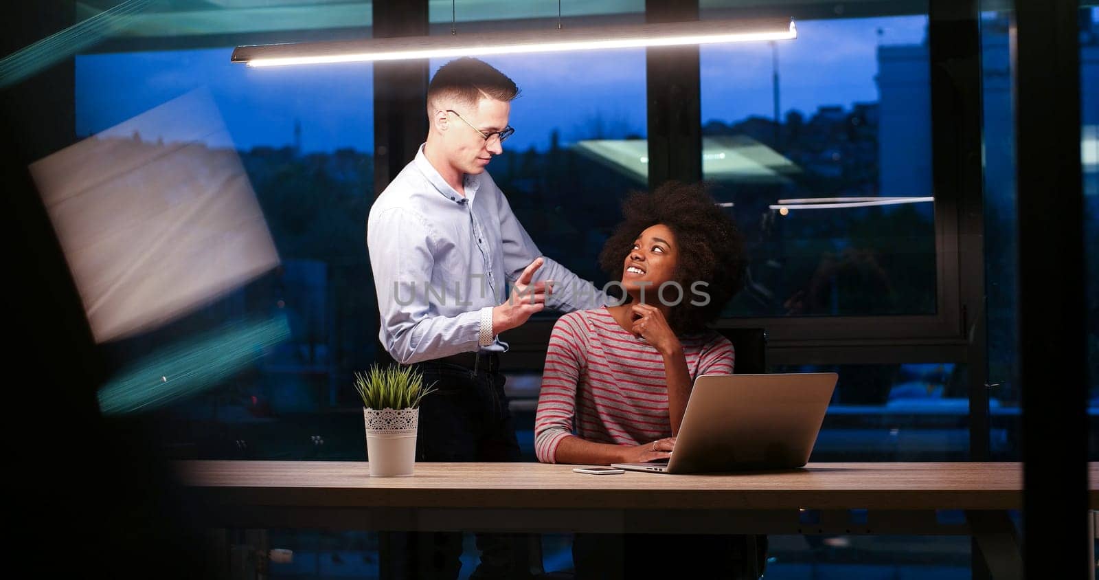 Multiethnic startup business team on meeting in modern night office interior brainstorming, working on laptop