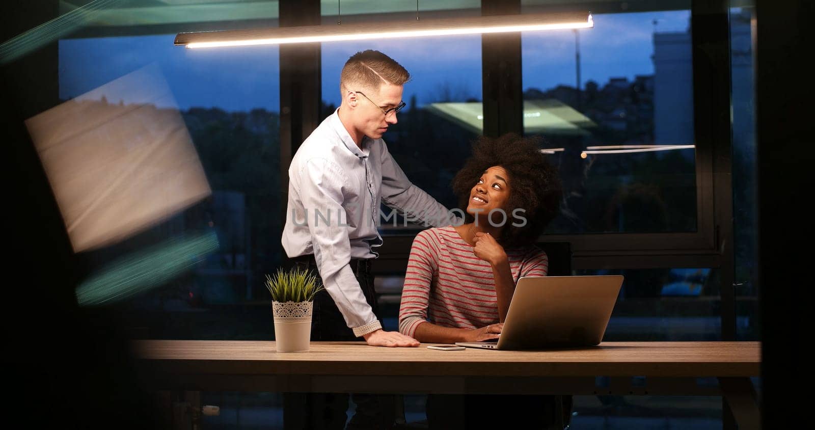 Multiethnic startup business team on meeting in modern night office interior brainstorming, working on laptop