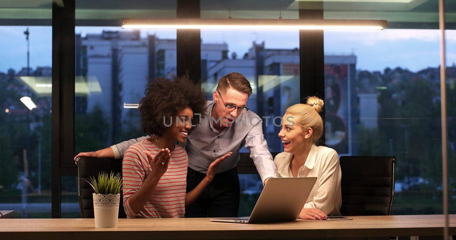 Multiethnic startup business team on meeting in modern night office interior brainstorming, working on laptop