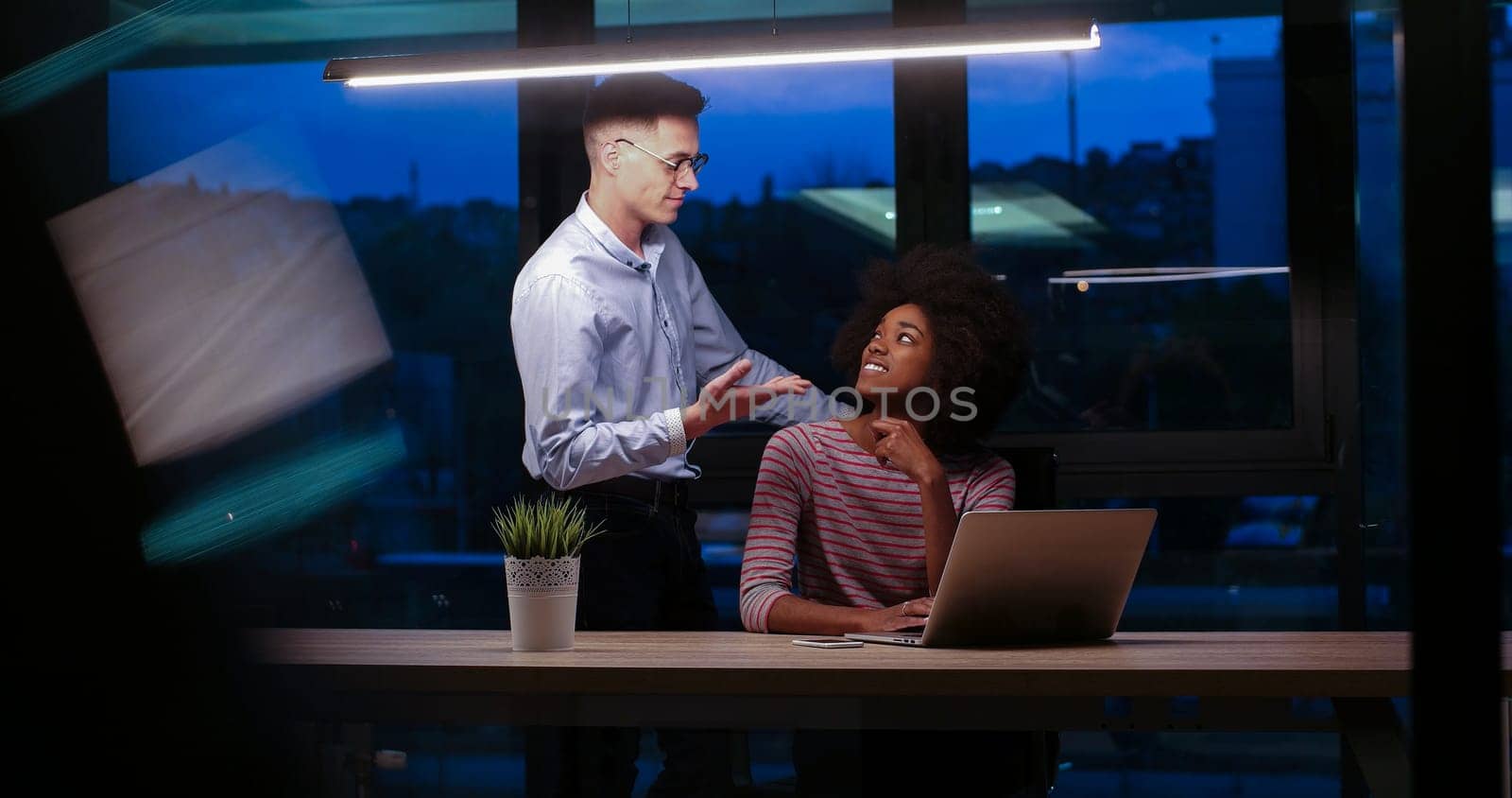 Multiethnic startup business team on meeting in modern night office interior brainstorming, working on laptop
