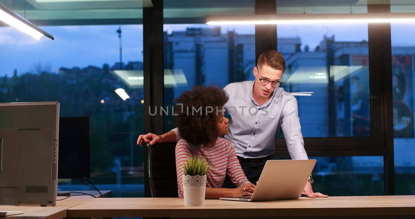 Multiethnic startup business team on meeting in modern night office interior brainstorming, working on laptop