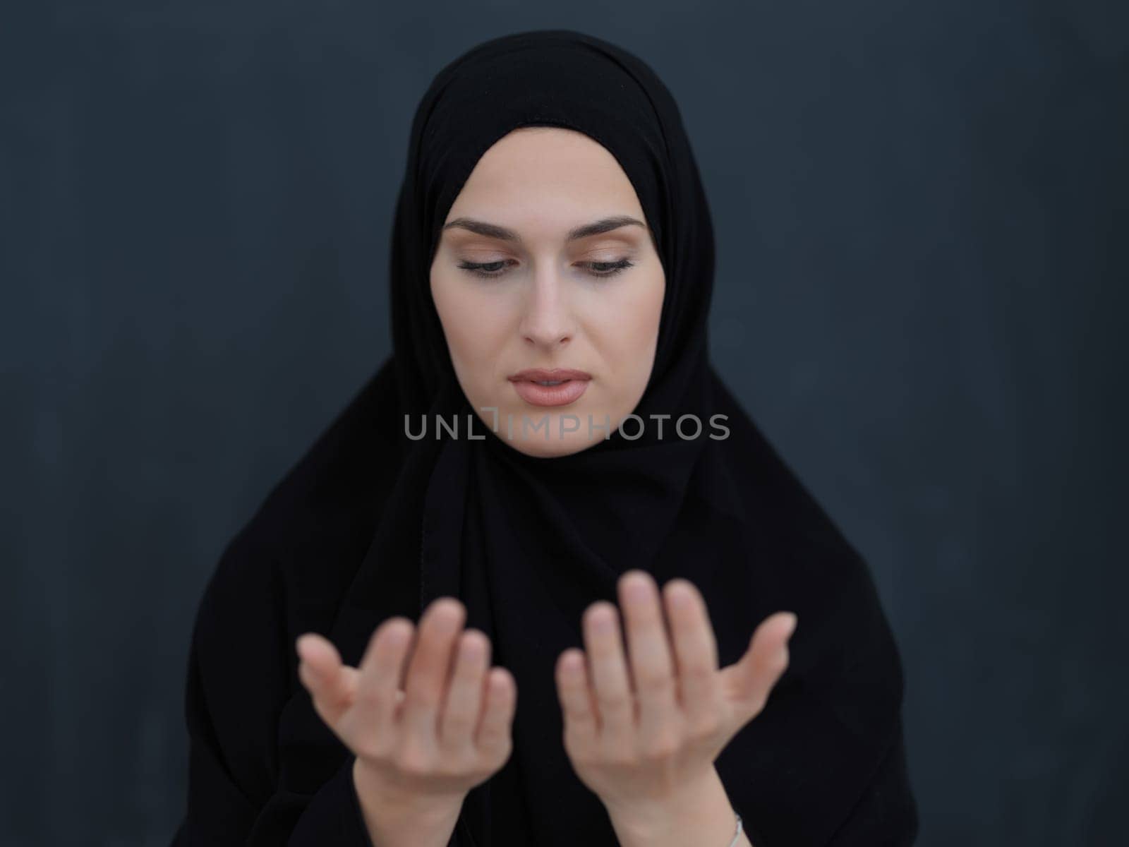 Portrait of young Muslim woman making dua. Arabian girl wearing abaya keeps hands in praying gesture. Representing worship to God and Ramadan Kareem concept