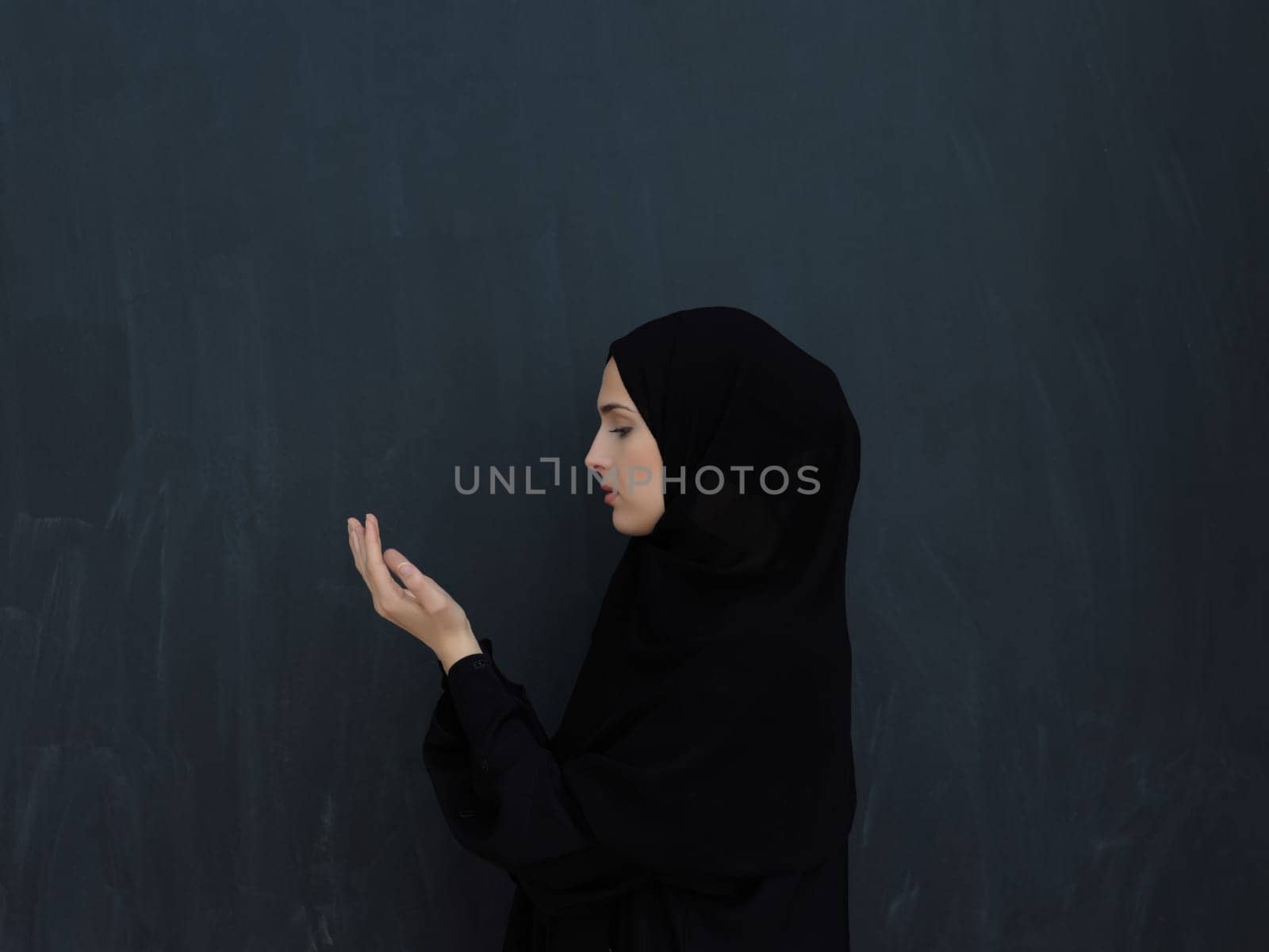 Portrait of young Muslim woman making dua. Arabian girl wearing abaya keeps hands in praying gesture. Representing worship to God and Ramadan Kareem concept