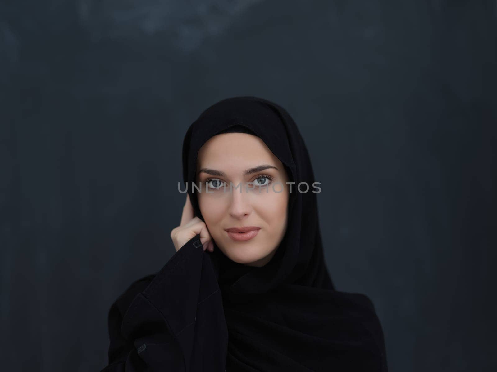 Young muslim businesswoman in traditional clothes or abaya talking on the smartphone. Arab woman in front of black chalkboard and representing techology, islamic fashion and Ramadan kareem concept