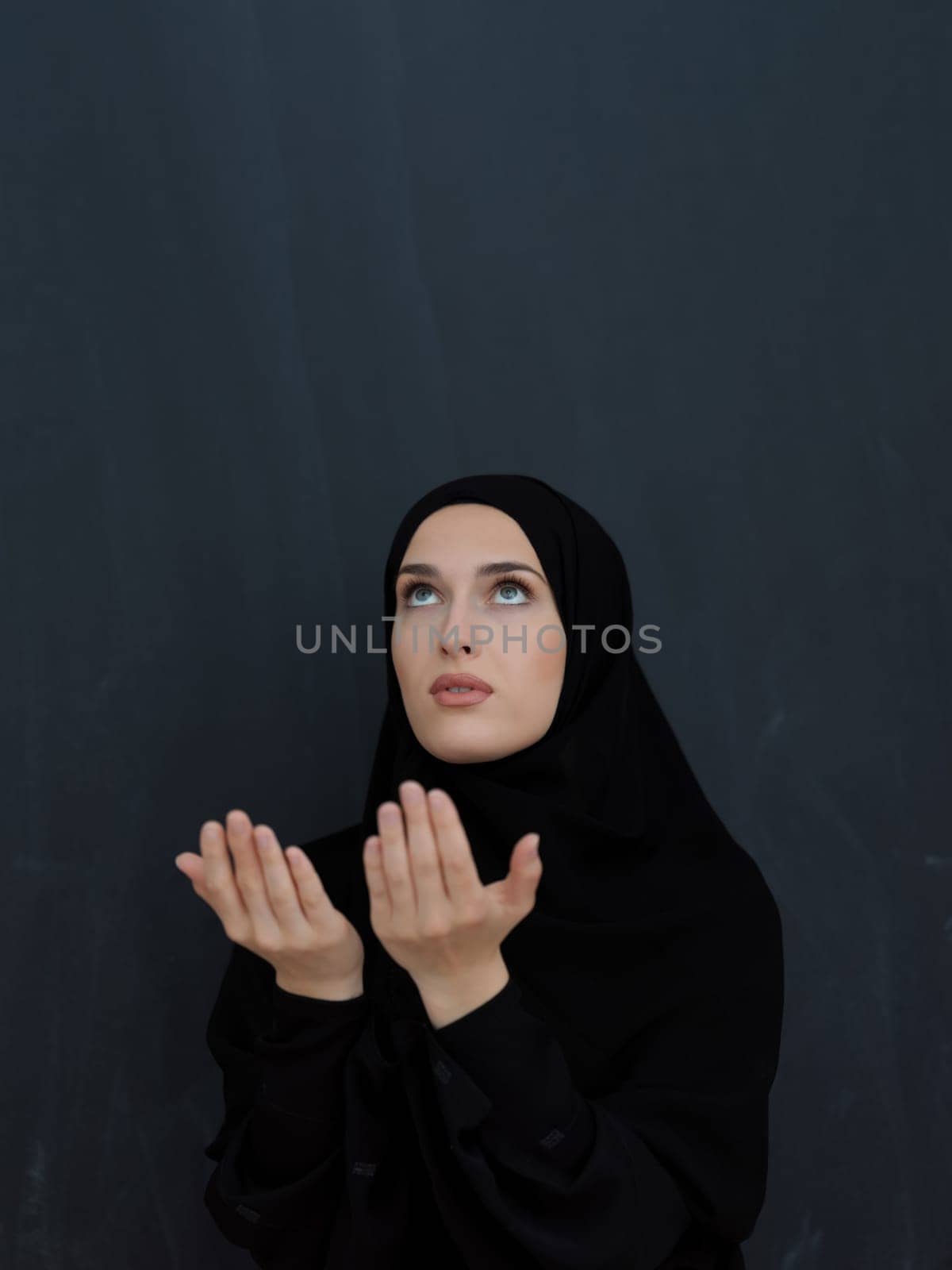 Portrait of young Muslim woman making dua. Arabian girl wearing abaya keeps hands in praying gesture. Representing worship to God and Ramadan Kareem concept