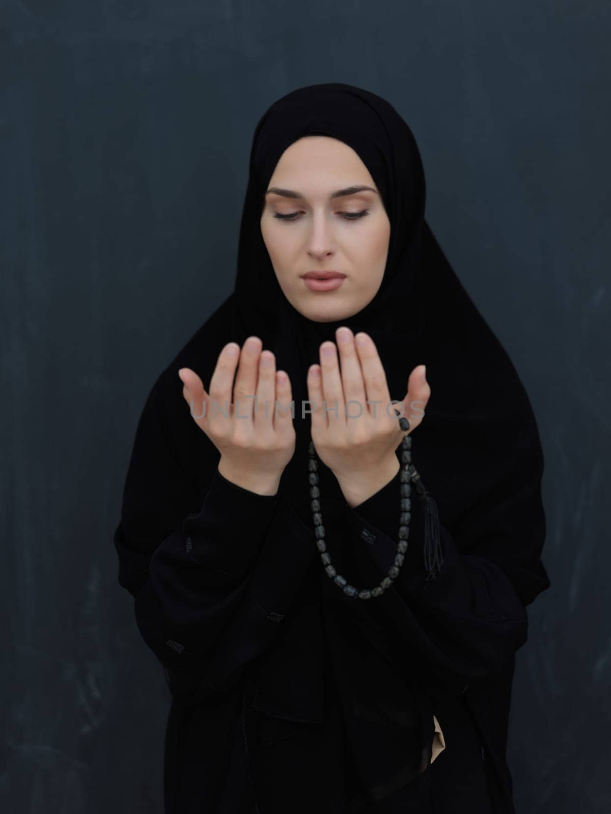 Portrait of young Muslim woman making dua. Arabian girl wearing abaya keeps hands in praying gesture. Representing worship to God and Ramadan Kareem concept