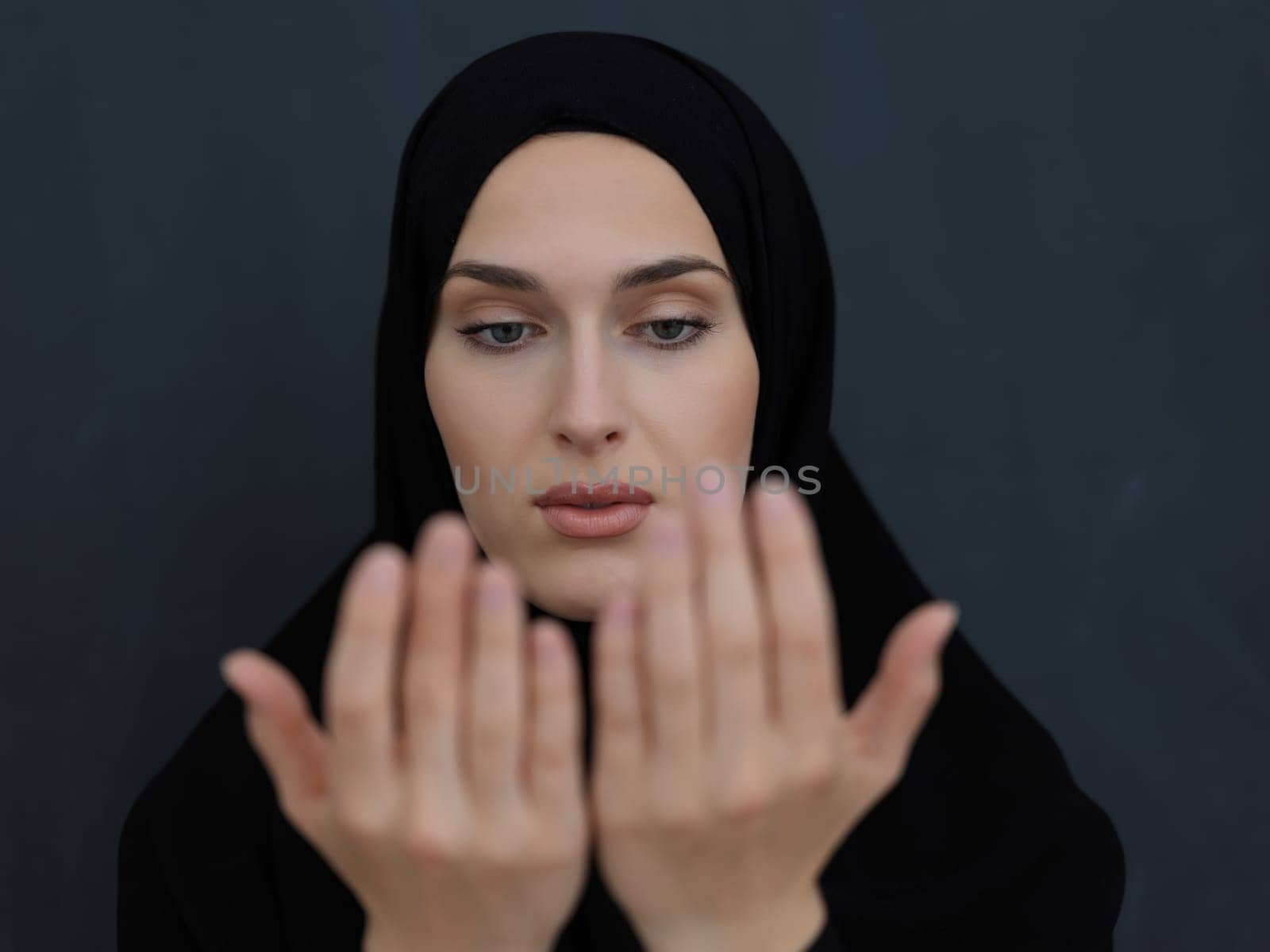Portrait of young Muslim woman making dua. Arabian girl wearing abaya keeps hands in praying gesture. Representing worship to God and Ramadan Kareem concept