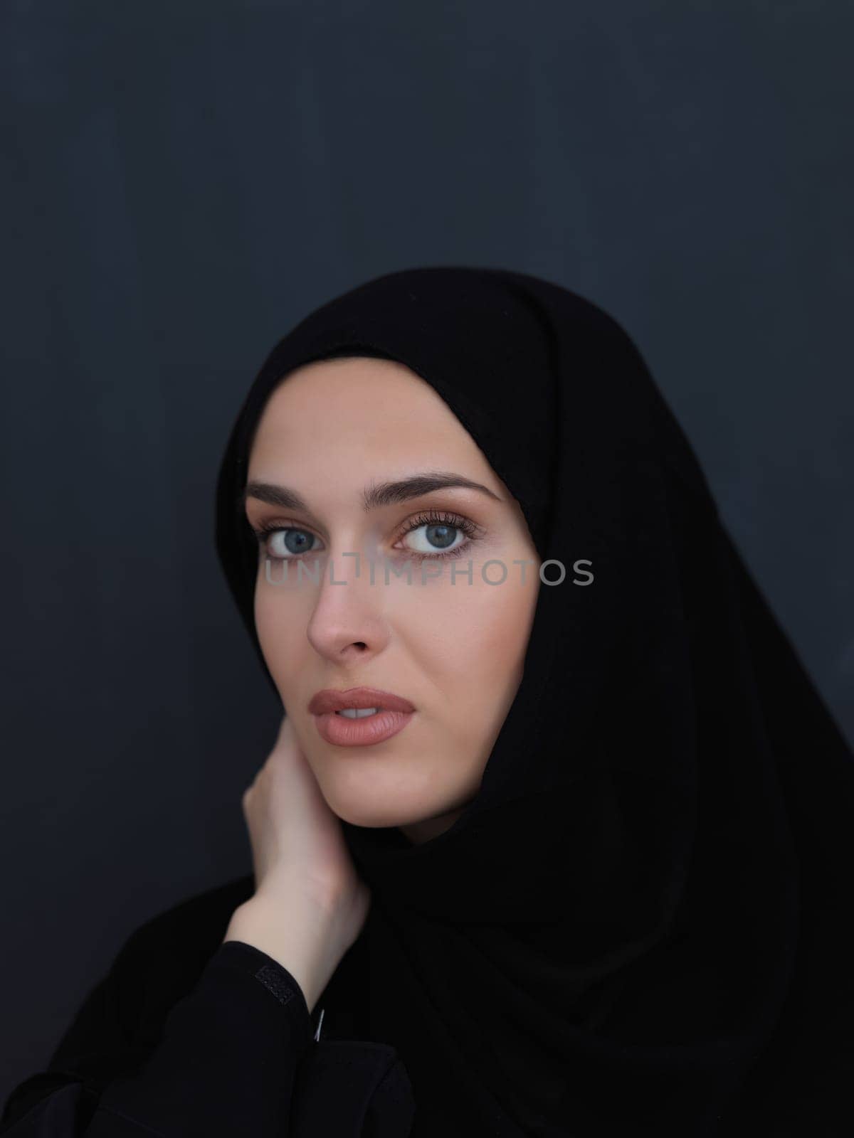 Portrait of modern young muslim woman in black abaya. Arab girl wearing traditional clothes and posing in front of black chalkboard. Representing modern and rich arabic lifestyle