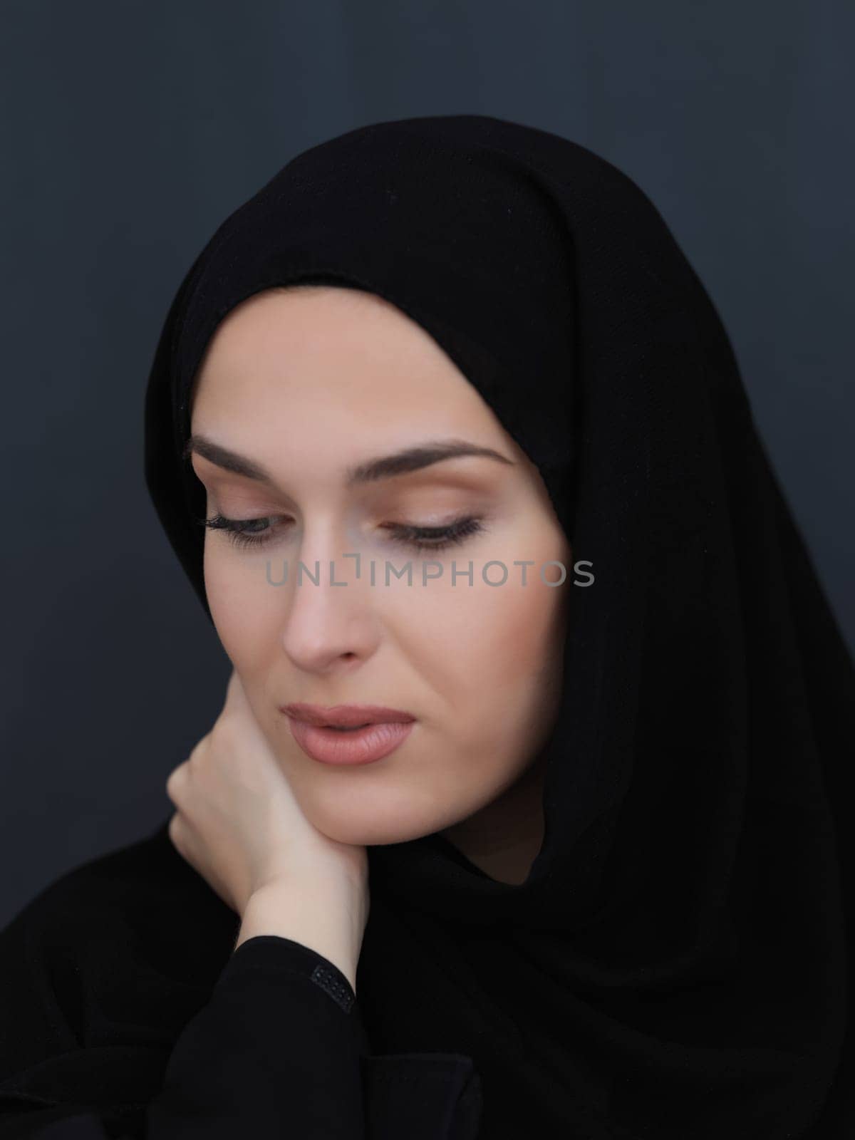 Portrait of modern young muslim woman in black abaya. Arab girl wearing traditional clothes and posing in front of black chalkboard. Representing modern and rich arabic lifestyle