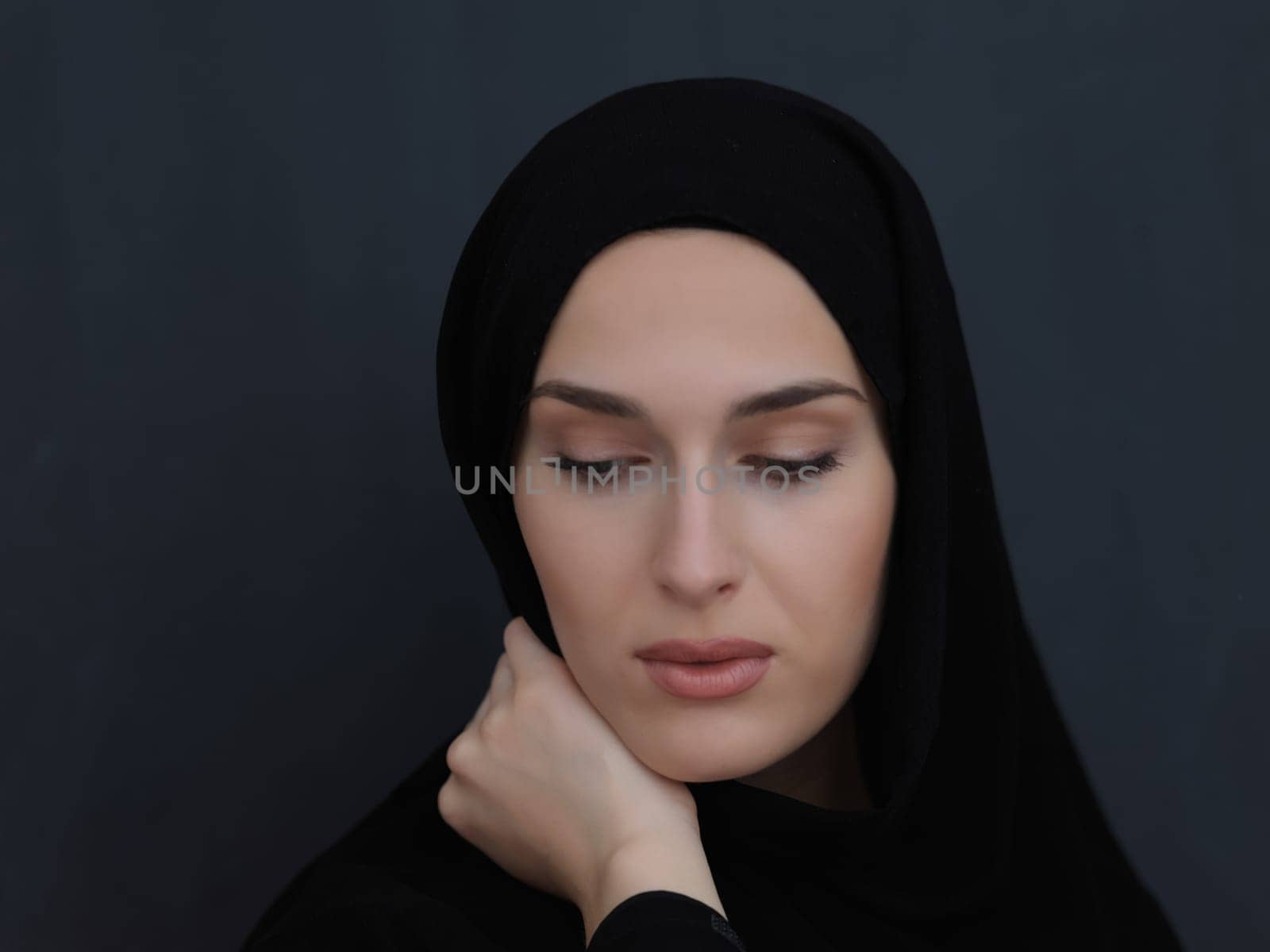 Portrait of modern young muslim woman in black abaya. Arab girl wearing traditional clothes and posing in front of black chalkboard. Representing modern and rich arabic lifestyle