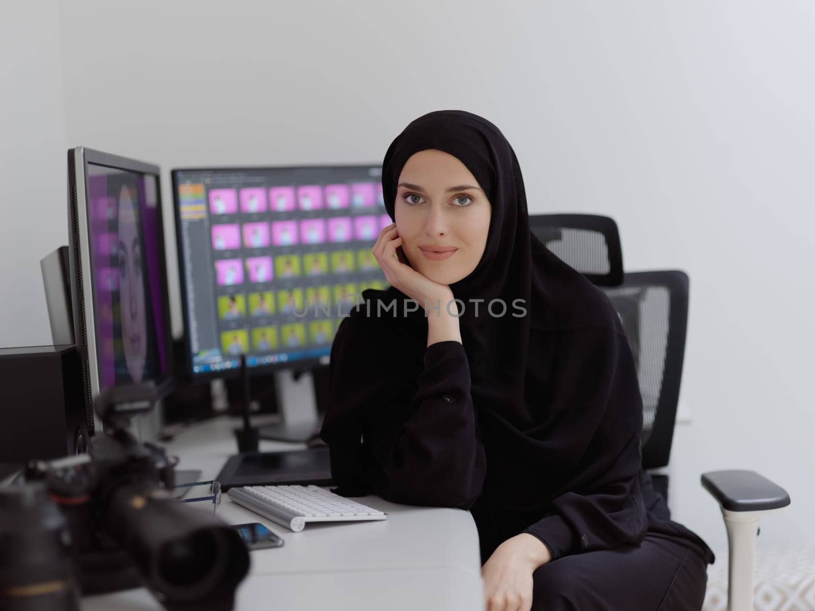 Portrait of young muslim female graphic designer. Hijab girl with the two monitors in background showing her work. Technology concept