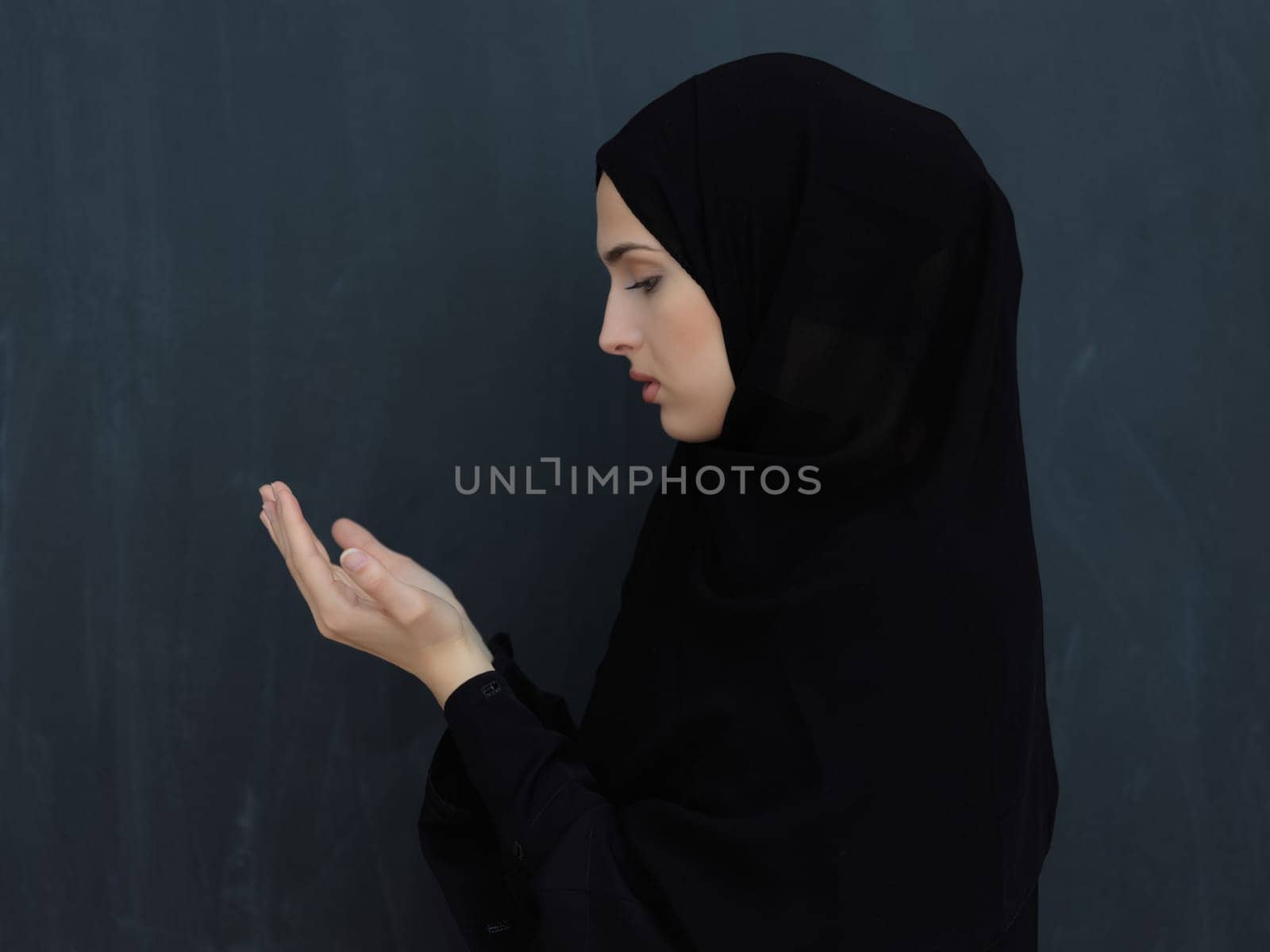 Portrait of young Muslim woman making dua. Arabian girl wearing abaya keeps hands in praying gesture. Representing worship to God and Ramadan Kareem concept