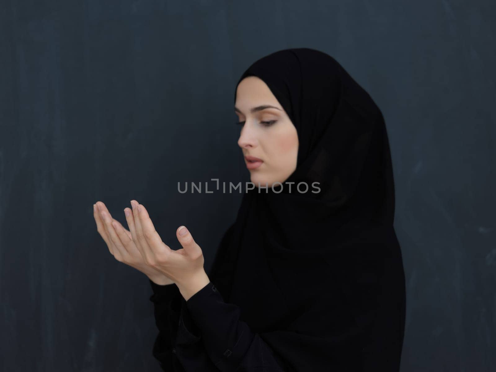 Portrait of young Muslim woman making dua. Arabian girl wearing abaya keeps hands in praying gesture. Representing worship to God and Ramadan Kareem concept