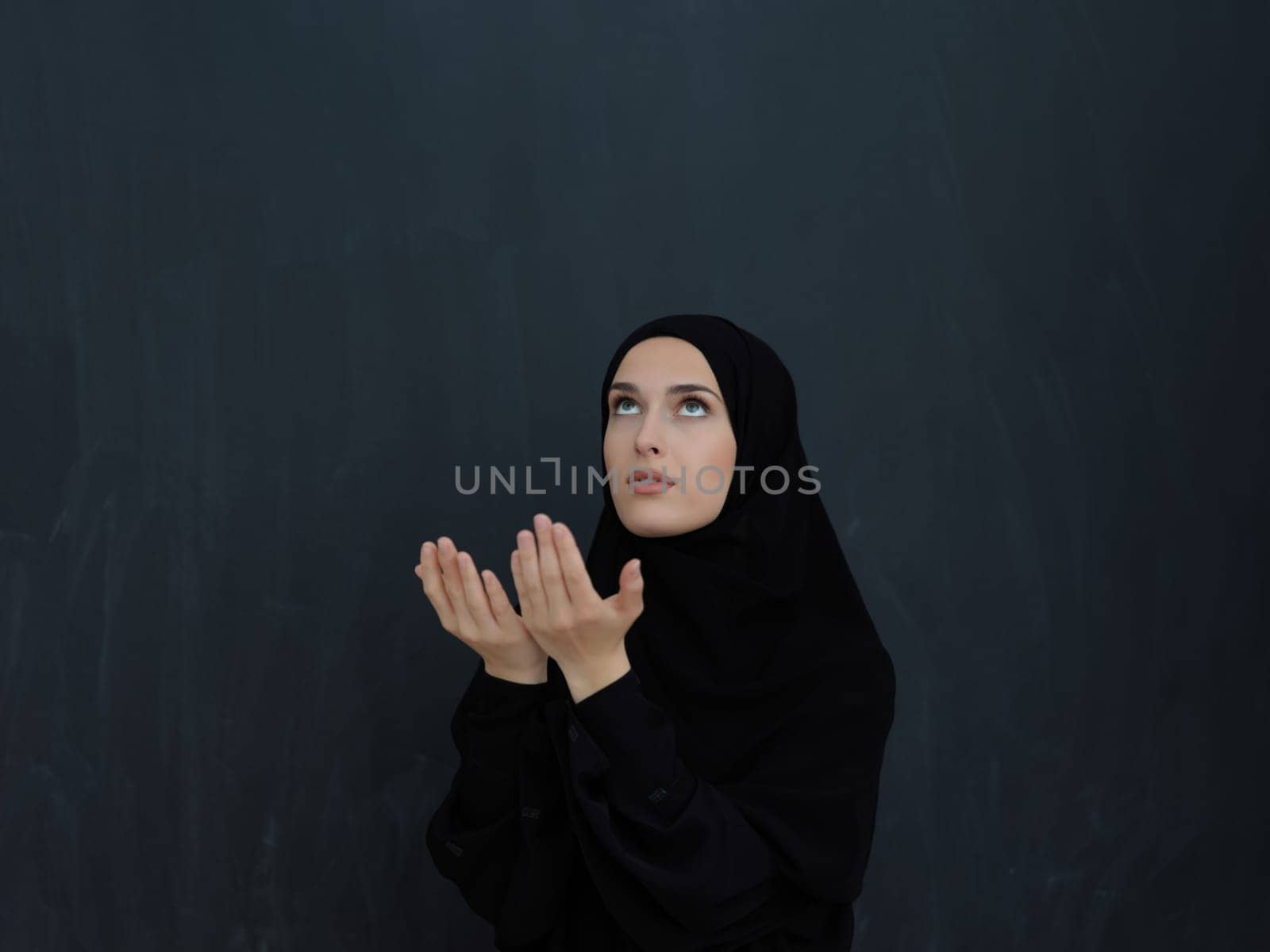 Portrait of young Muslim woman making dua. Arabian girl wearing abaya keeps hands in praying gesture. Representing worship to God and Ramadan Kareem concept