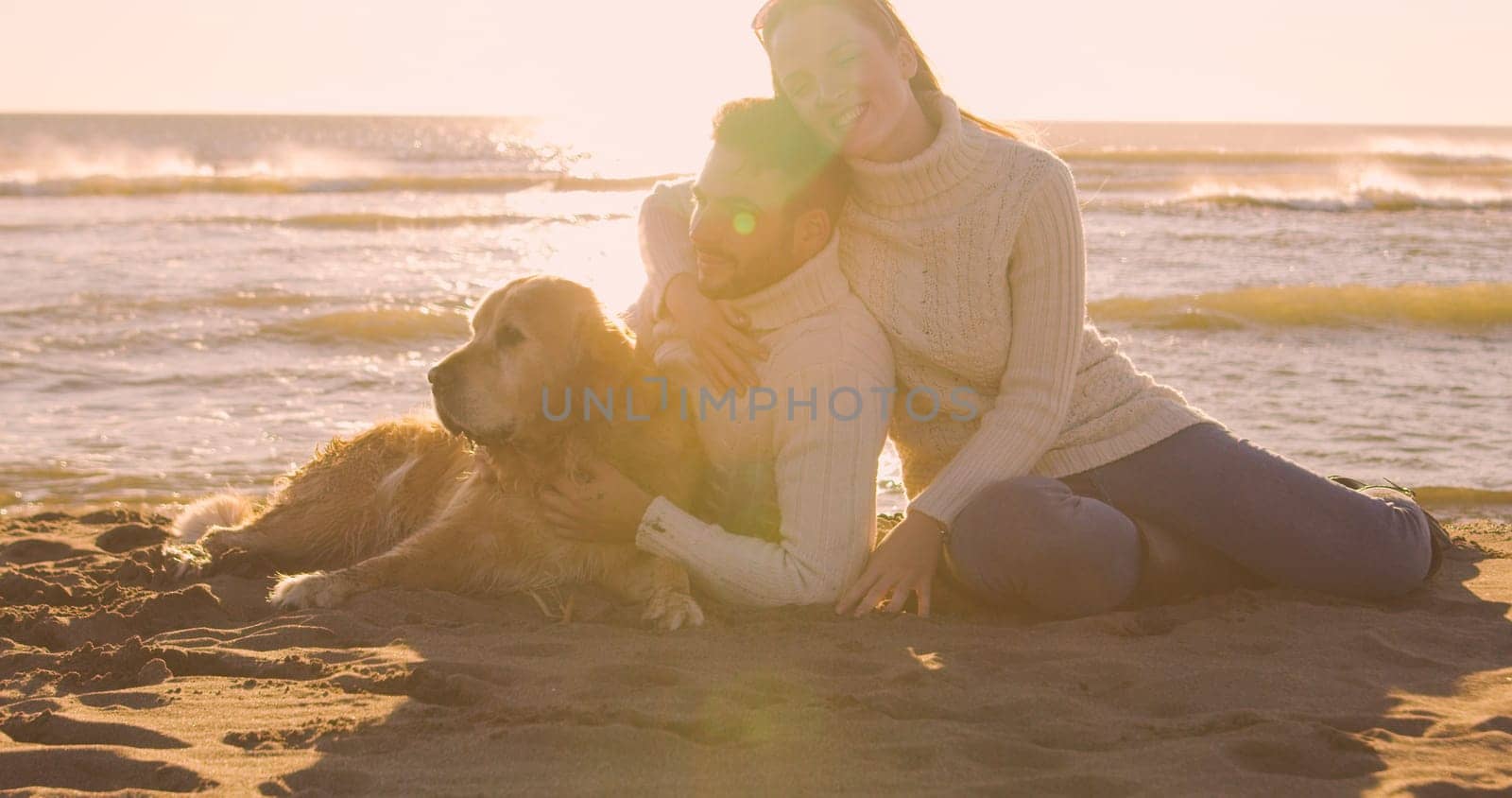 Couple With A Dog enjoying time  together On The Beach at autumn day