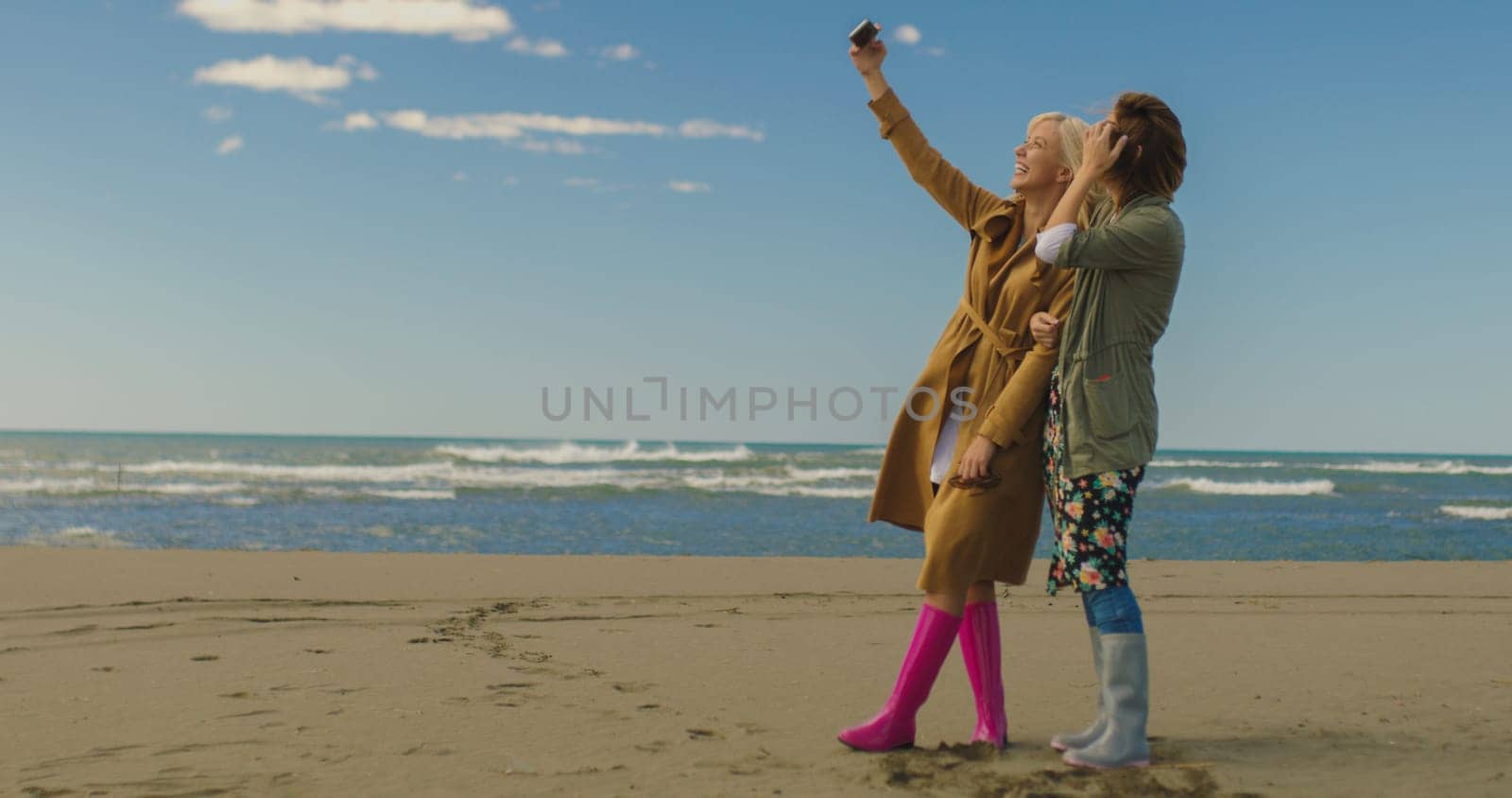 Friends making selfie. two beautiful young women making selfie at autumn day on the beach