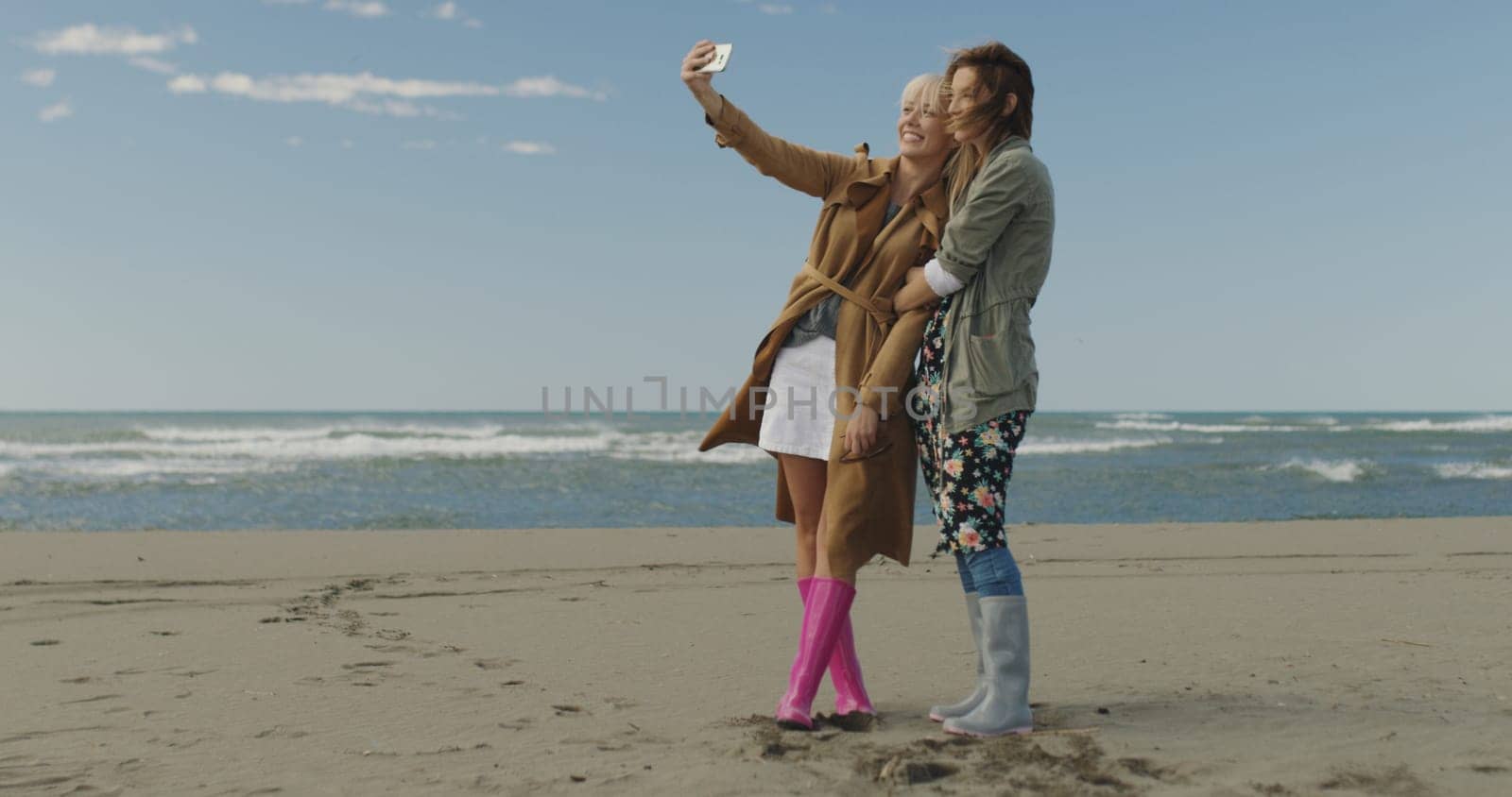 Friends making selfie. two beautiful young women making selfie at autumn day on the beach