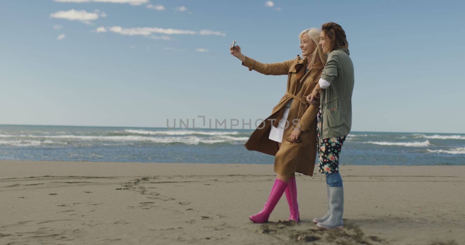 Friends making selfie. two beautiful young women making selfie at autumn day on the beach