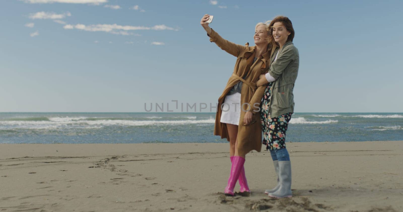 Friends making selfie. two beautiful young women making selfie at autumn day on the beach
