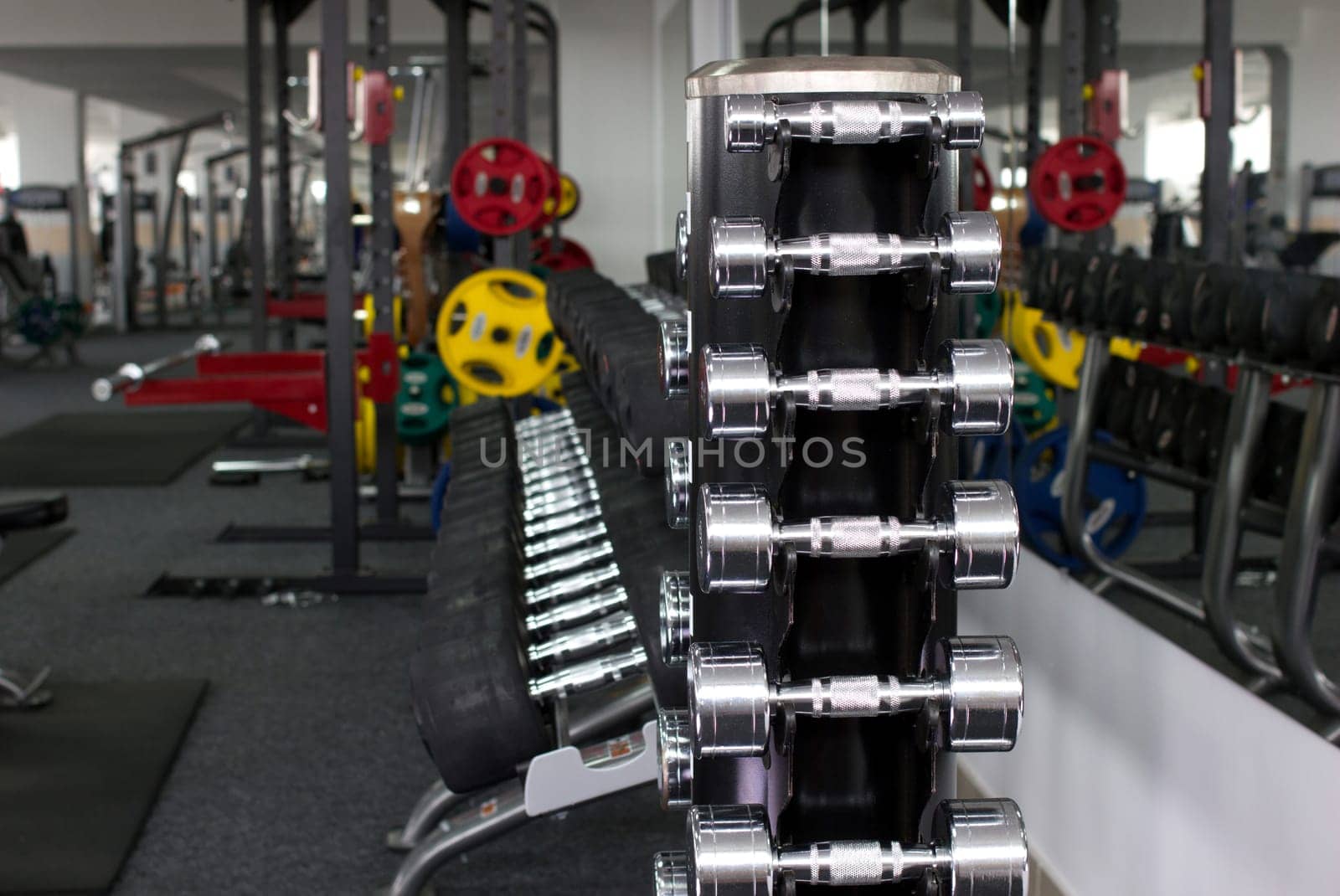 many dumbbells and other sport's equipments in gymnasium on blurred background