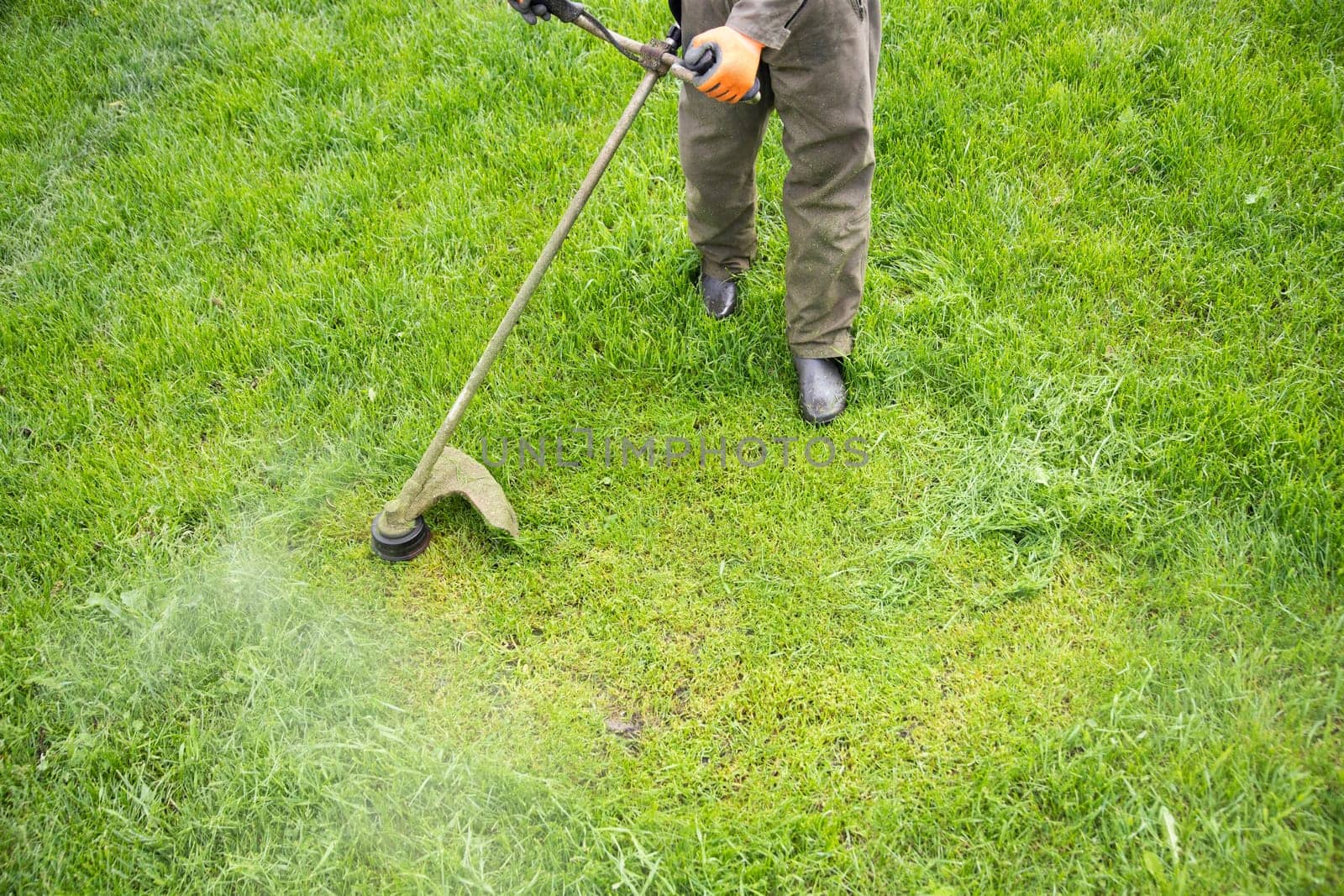 Mowing the grass with a lawn mower. Garden work concept background.