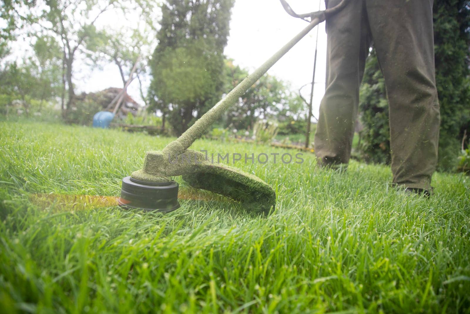 Mowing the grass with a lawn mower. Garden work concept background.