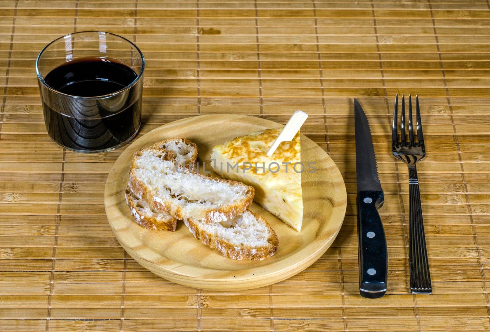 Spanish tortilla skewer presented in typical ration of Spain, With bread and a glass of red wine