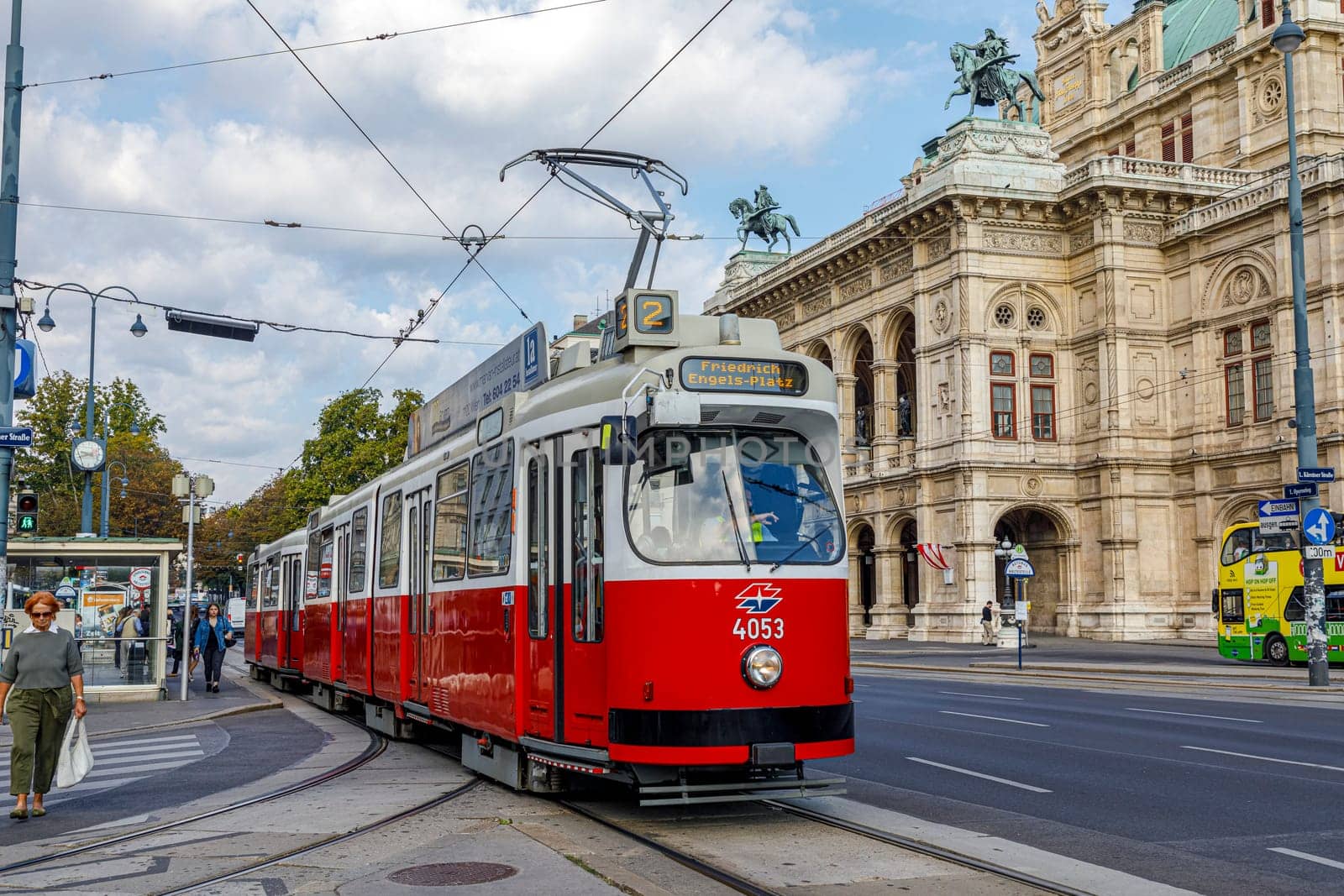 Vienna, Austria - September 16, 2019: people in streetcar in front of Vienna State Opera house - the Hofburg - with history dating back to mid-19th century. It is located in centre of Vienna