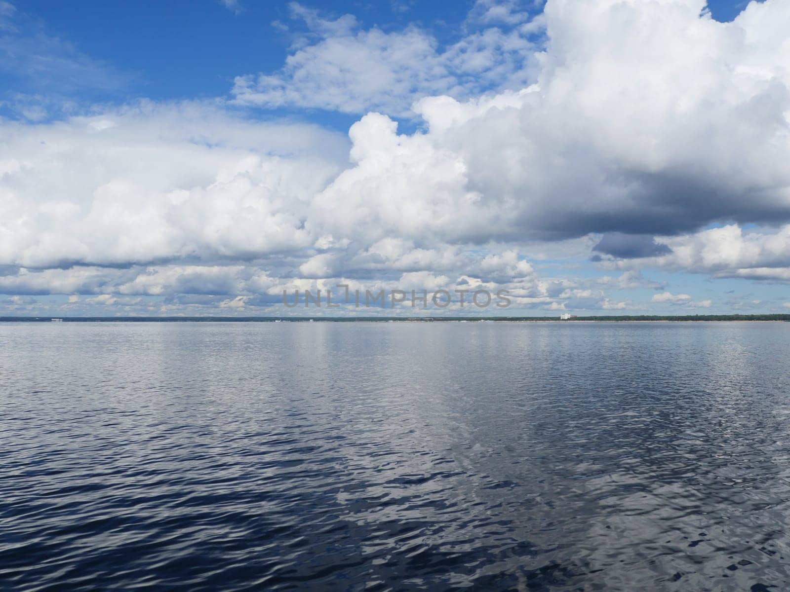 Seascape cumulus clouds and blue sky are reflected in the sea