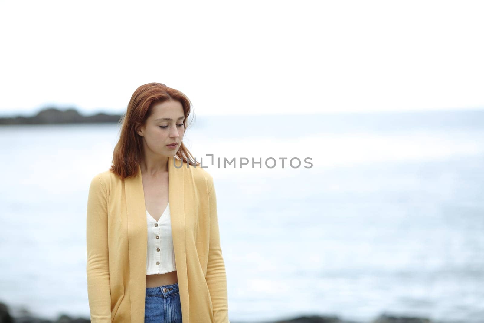 Sad pensive woman walking alone on the beach