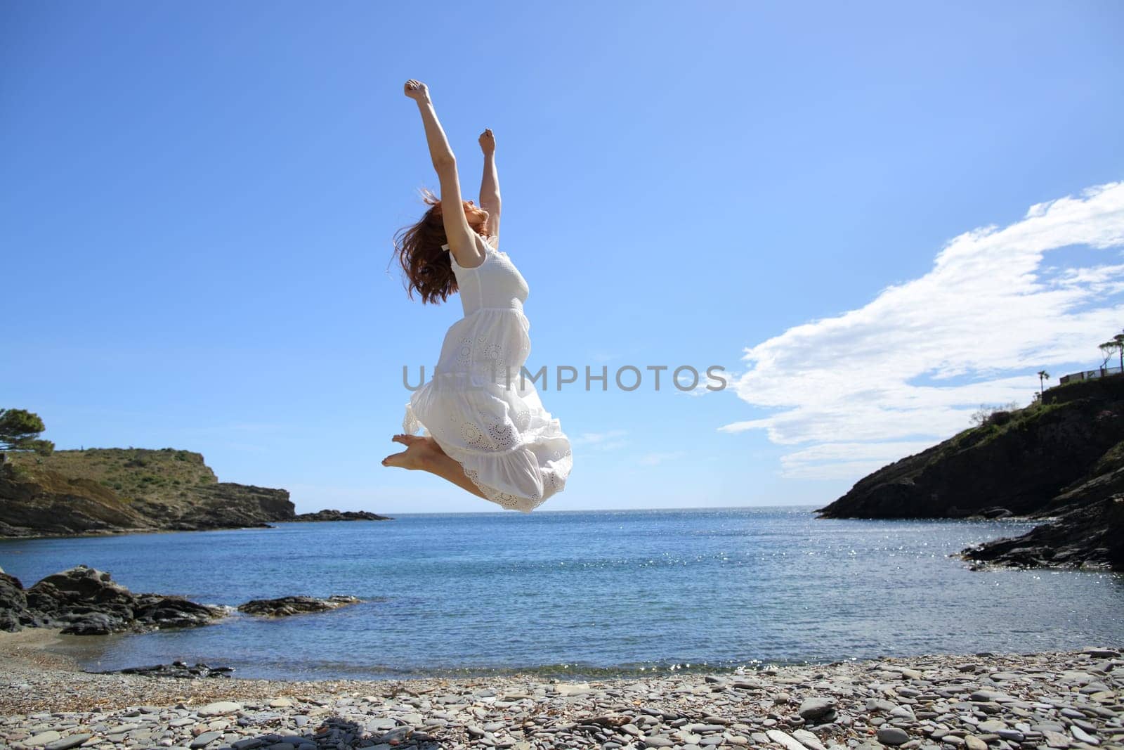 Happy tourist on the beach celebrating vacation raising arms