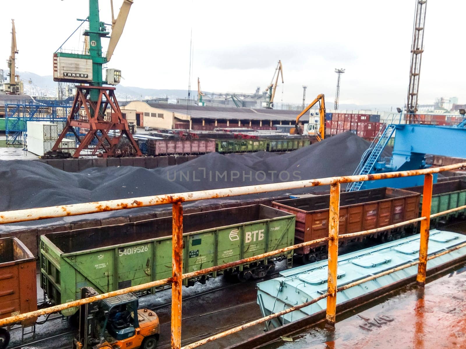 Novorossiysk, Russia - August 20, 2017: Cargo industrial port, port cranes. Loading of anthracite. Transportation of coal. Heap of coal