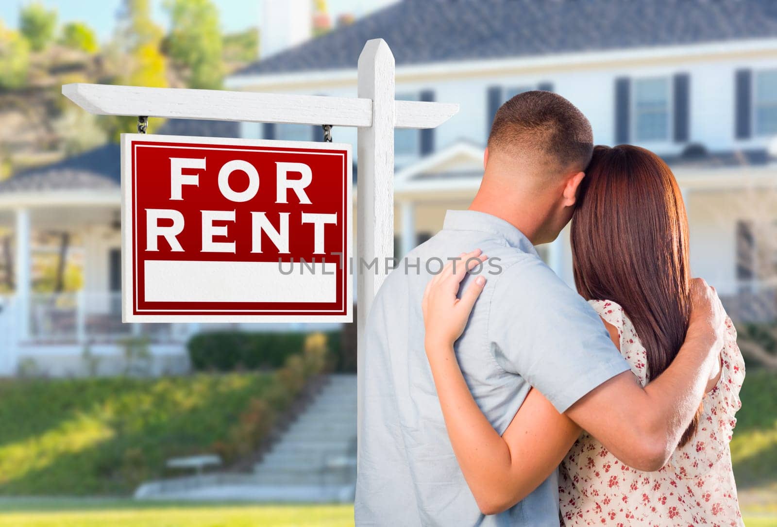 Military Couple Looking At House with For Rent Real Estate Sign In Front.
