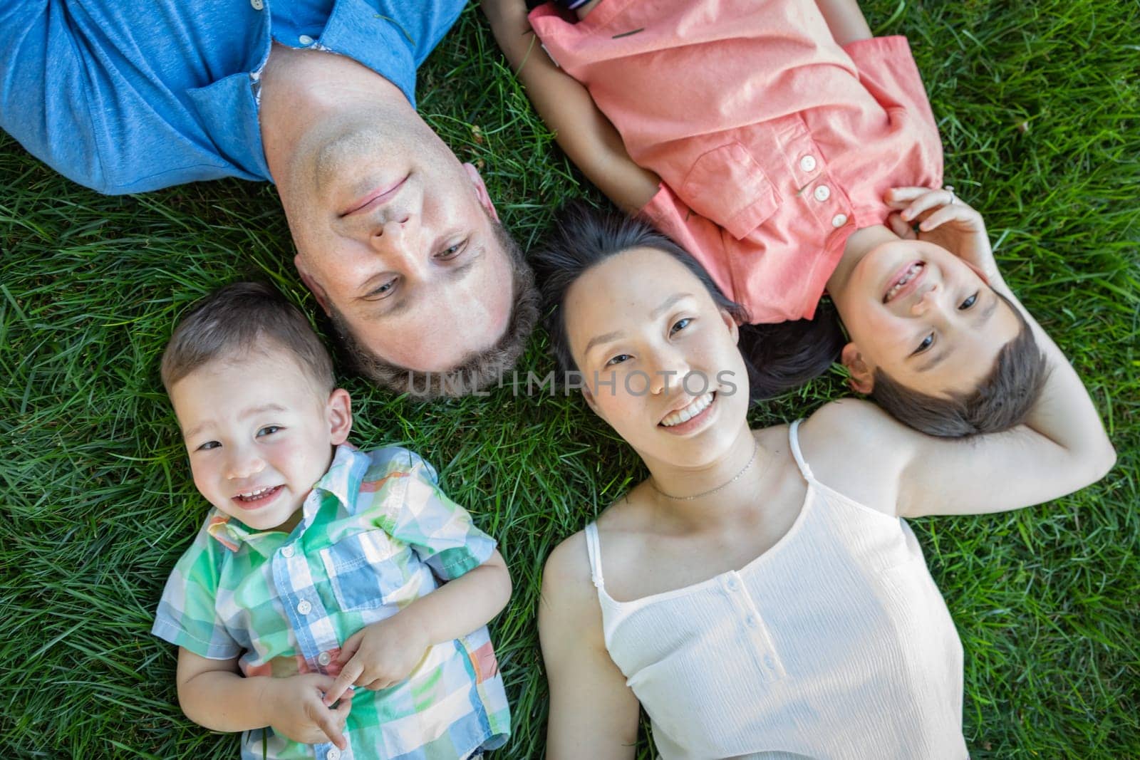 Chinese Mother, Caucasian Father and Mixed Race Children Laying On Grass.