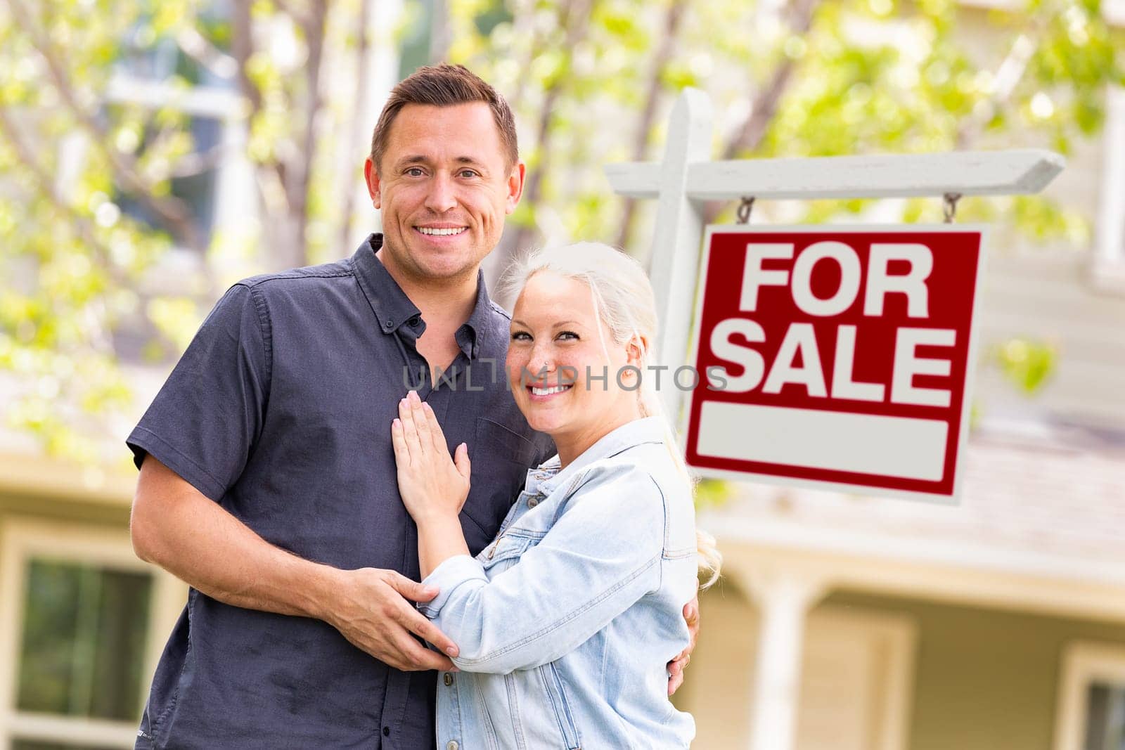 Caucasian Couple in Front of For Sale Real Estate Sign and House