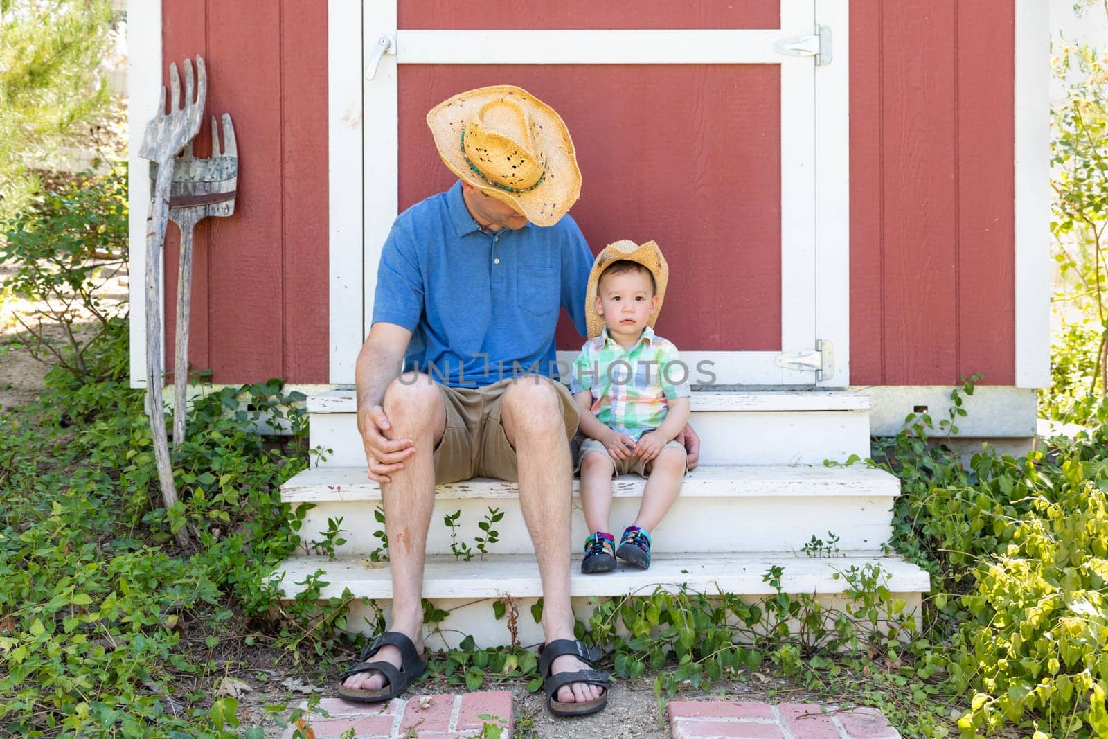 Playful Young Caucasian Father and Mixed Race Chinese Son Wearing Cowboy Hats