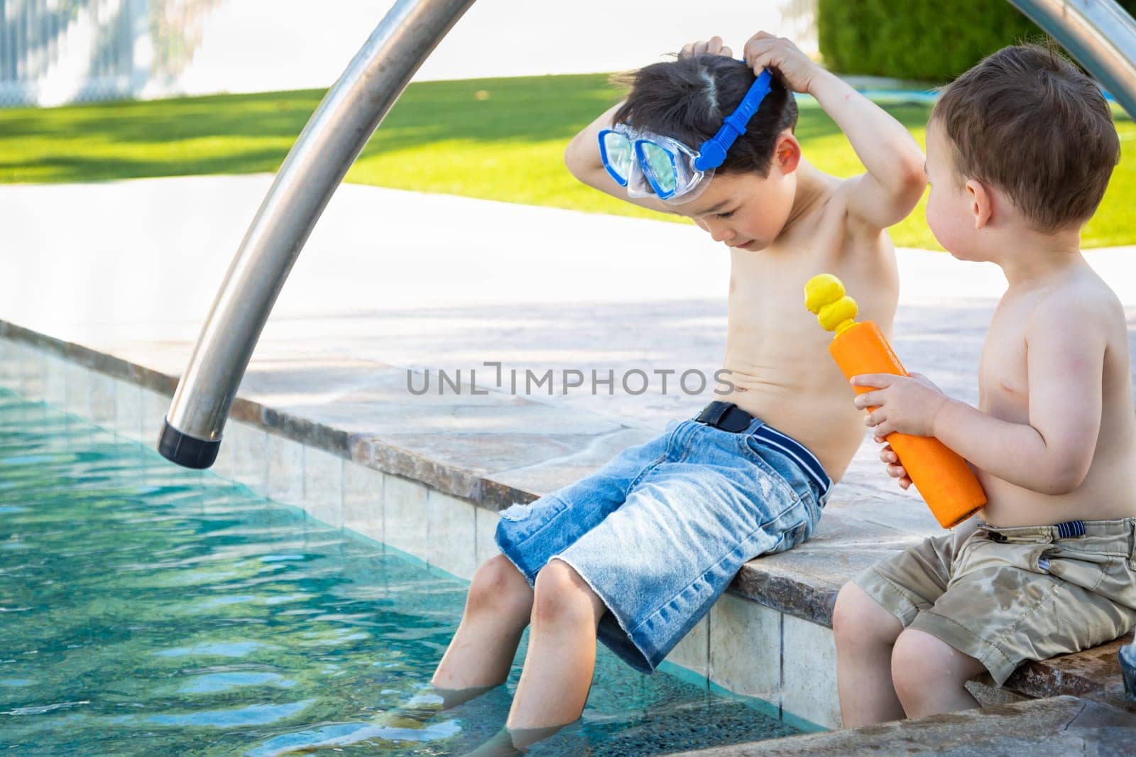 Young Mixed Race Chinese and Caucasian Brothers Wearing Swimming Goggles Playing At The Pool